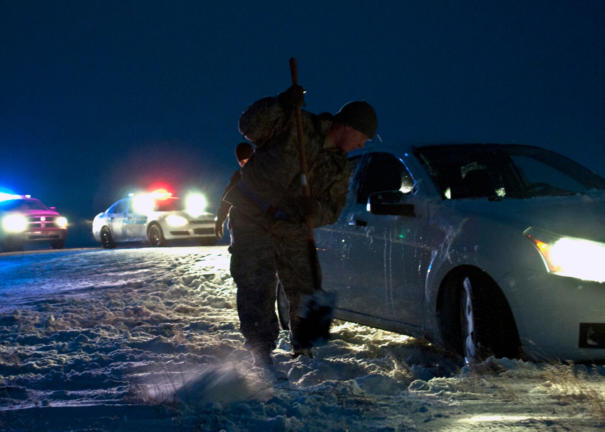 An Airman digs out a stranded driver just driver just outside the Mountain Home Air Force Base main gate, Jan. 10, 2013. Tech. Sgt. Barry Williams, 366th Security Forces Squadron, and three other servicemembers, assisted the stranded driver. (U.S. Air Force photo/Master Sgt. Kevin Wallace/RELEASED)