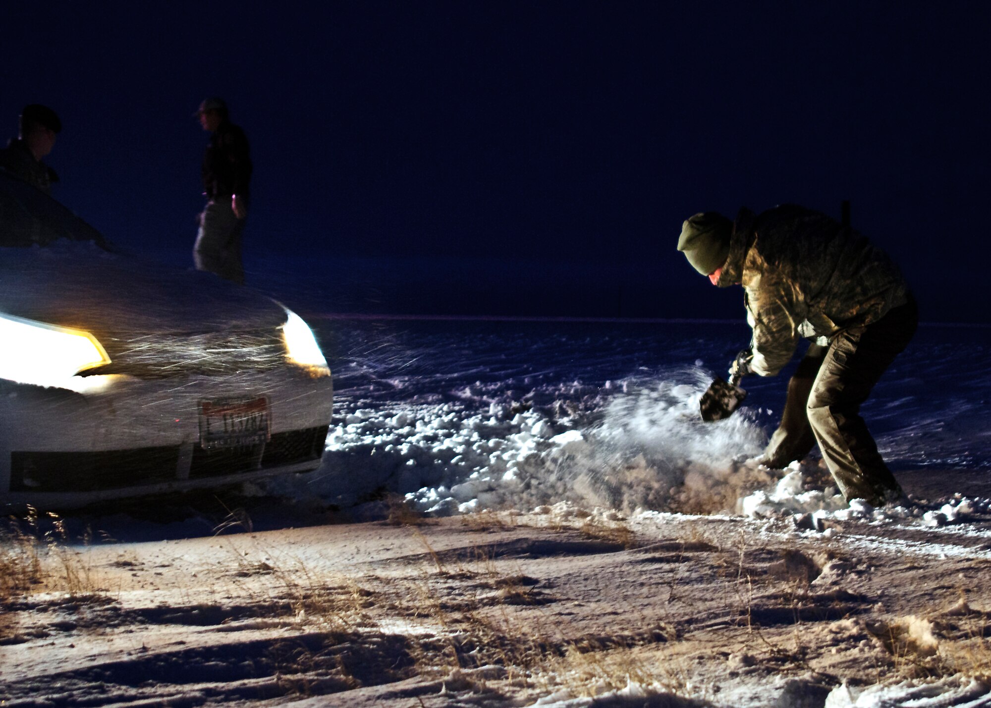 An Airman digs out a stranded driver just driver just outside the Mountain Home Air Force Base main gate, Jan. 10, 2013. Tech. Sgt. Barry Williams, 366th Security Forces Squadron, and three other servicemembers, assisted the stranded driver. (U.S. Air Force photo/Master Sgt. Kevin Wallace/RELEASED)