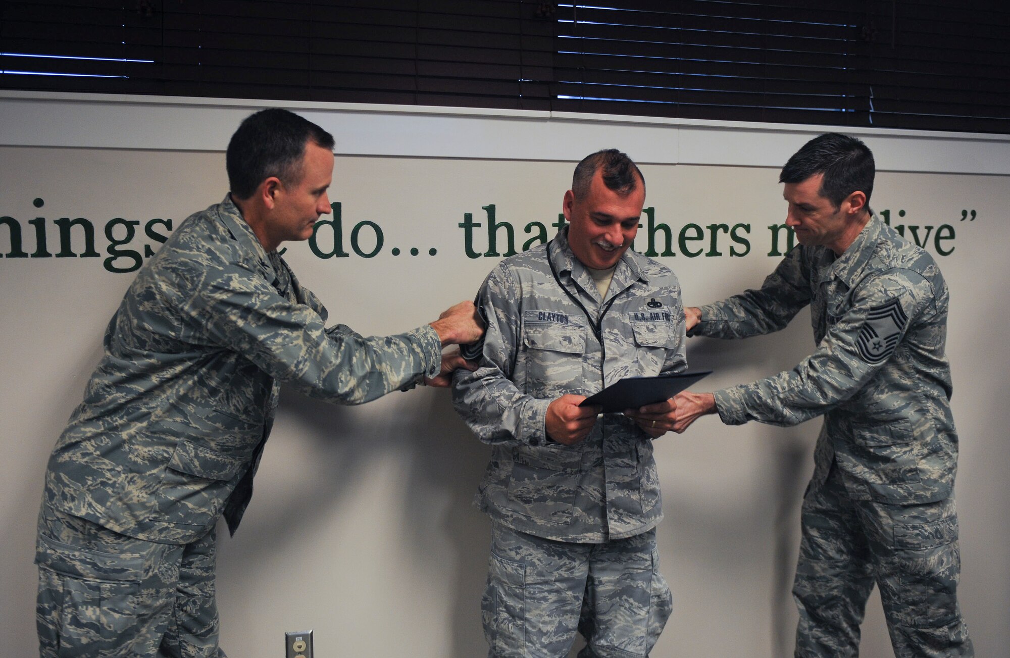 U.S. Air Force Senior Master Sgt. Roy Clayton, 75th Aircraft Maintenance Unit superintendent, receives chief master sergeant stripes from Col. Billy Thompson, 23d Wing commander, and Chief Master Sgt. Matthew Wells, 347th Rescue Group superintendent, during a surprise promotion at Moody Air Force Base, Ga., Jan. 10, 2013. Clayton was in a meeting when Thompson along with other base group commanders and chiefs came by to deliver the news. (U.S. Air Force photo by Airman 1st Class Olivia Bumpers/Released)