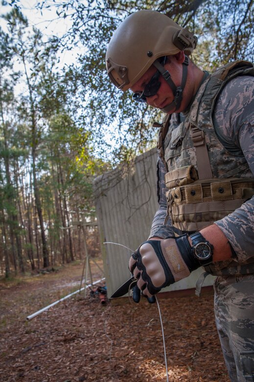 Staff Sgt. Edward Garwick, 628th Civil Engineer Squadron explosive ordnance disposal technician, uses a knife to strip a wire used to detonate an improvised explosive device during a routine training exercise Jan. 8, 2013, at Joint Base Charleston - Air Base, S.C. Command wire is a hair-thin, bare copper strand that only the sharpest eye can see. The training equips EOD members in how locate and pinpoint these command wires that may be attached to explosive devices in remote areas during deployments. (U.S. Air Force photo/Airman 1st Class Ashlee Galloway)