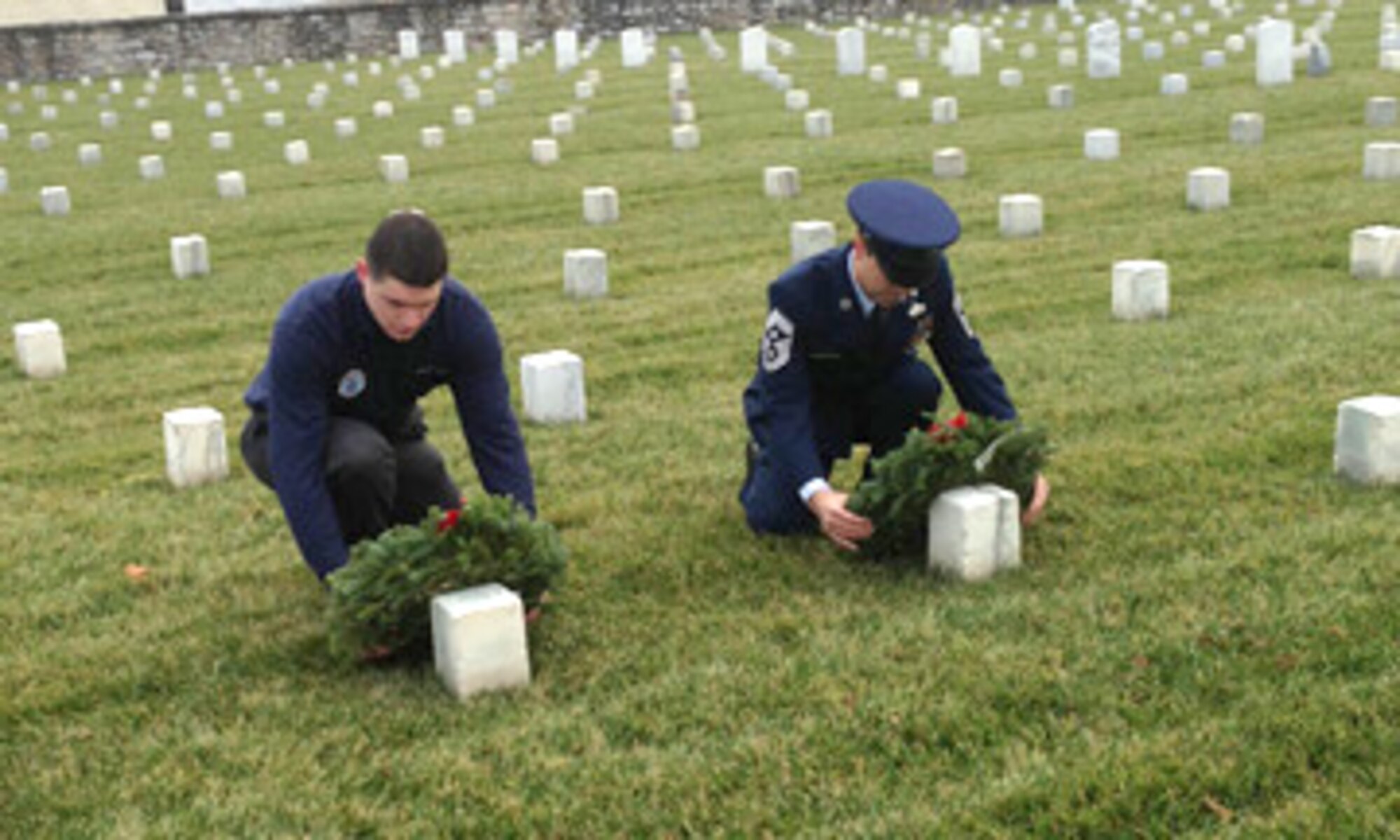 Senior Airman Jacob Bixler and Command Chief Master Sgt. Ronald Glazer place wreaths on the graves of veterans at the Winchester National Cemetary in Winchester, Va.,  as part of the Wreaths Across America event