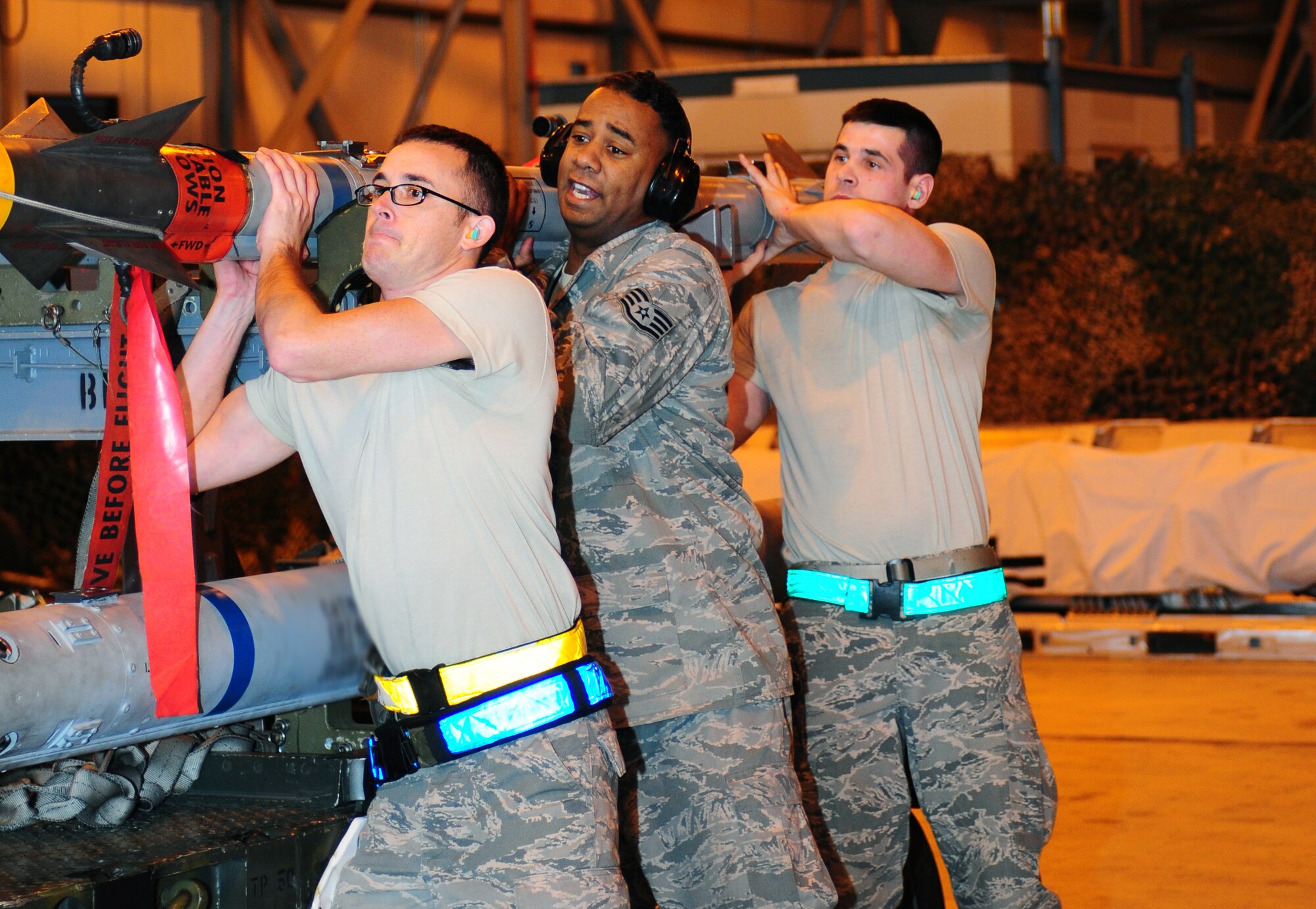 ROYAL AIR FORCE LAKENHEATH, England - (From left) Senior Airman Jared Gregory, weapons load crew member, Staff Sgt. Ahmed Foster, weapons load crew team chief and Airman 1st Class Justin Francisco, weapons load crew member, 493rd Aircraft Maintenance Unit, lift an AIM-9 munition off of a trailer during the quarterly load crew competition Jan. 7, 2013. The winner is determined by the fastest time loading munitions with the least amount of errors. (U.S. Air Force photo by Airman 1st Class Dana J. Butler)

