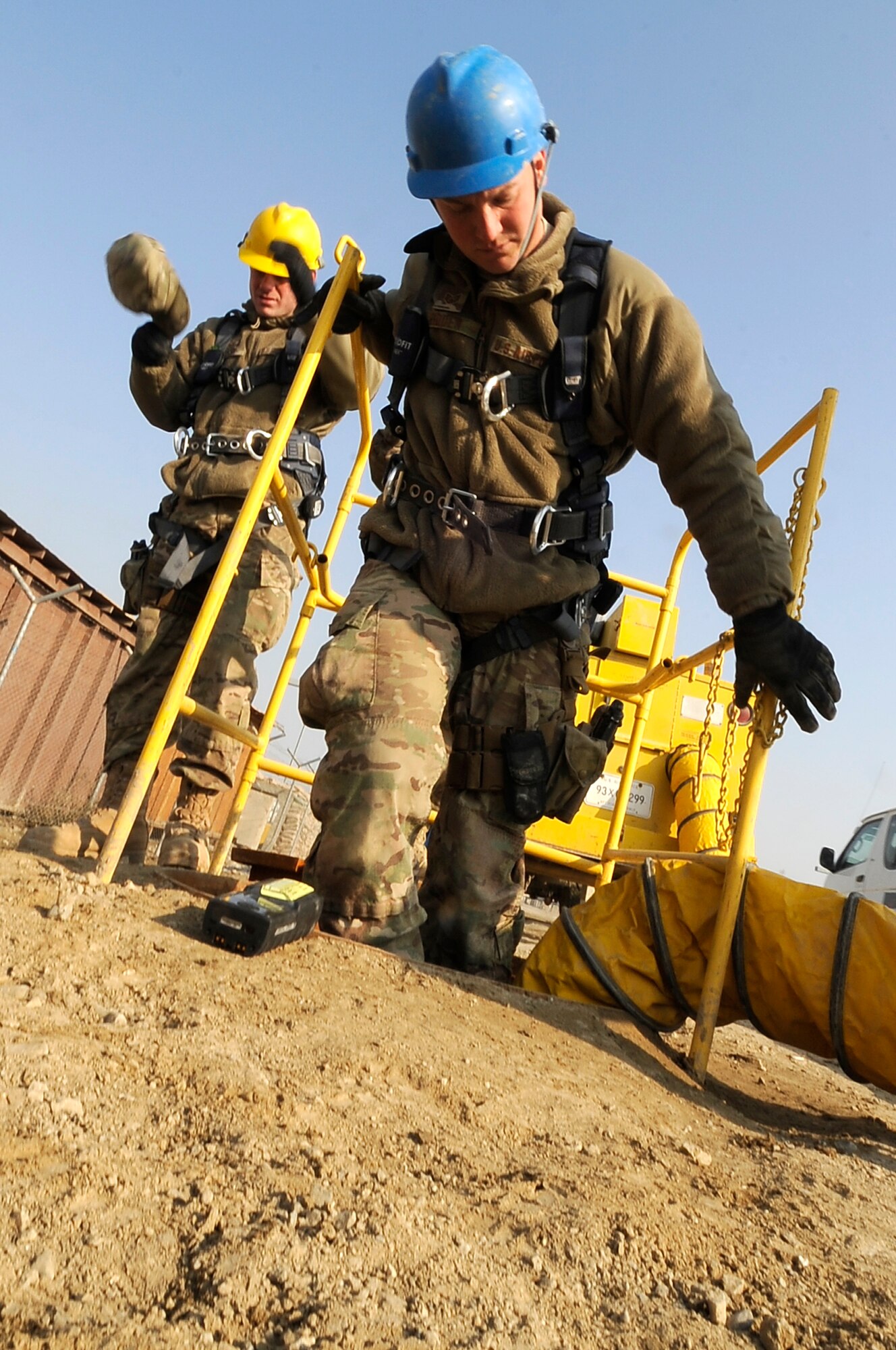 Staff Sgt. Brian Hidden of the 455th Expeditionary Communications Squadron, cable and antenna systems technician, descends underground as Staff Sgt. Brian Olsen, 455th ECS, gears up to do a final inspection of communication on Bagram Airfield, Jan. 9, 2013. Hidden and Olsen will ensure the cables are properly spliced and encased as the base prepares for future development. (U.S. Air Force Photo/Master Sgt. Jun Kim)