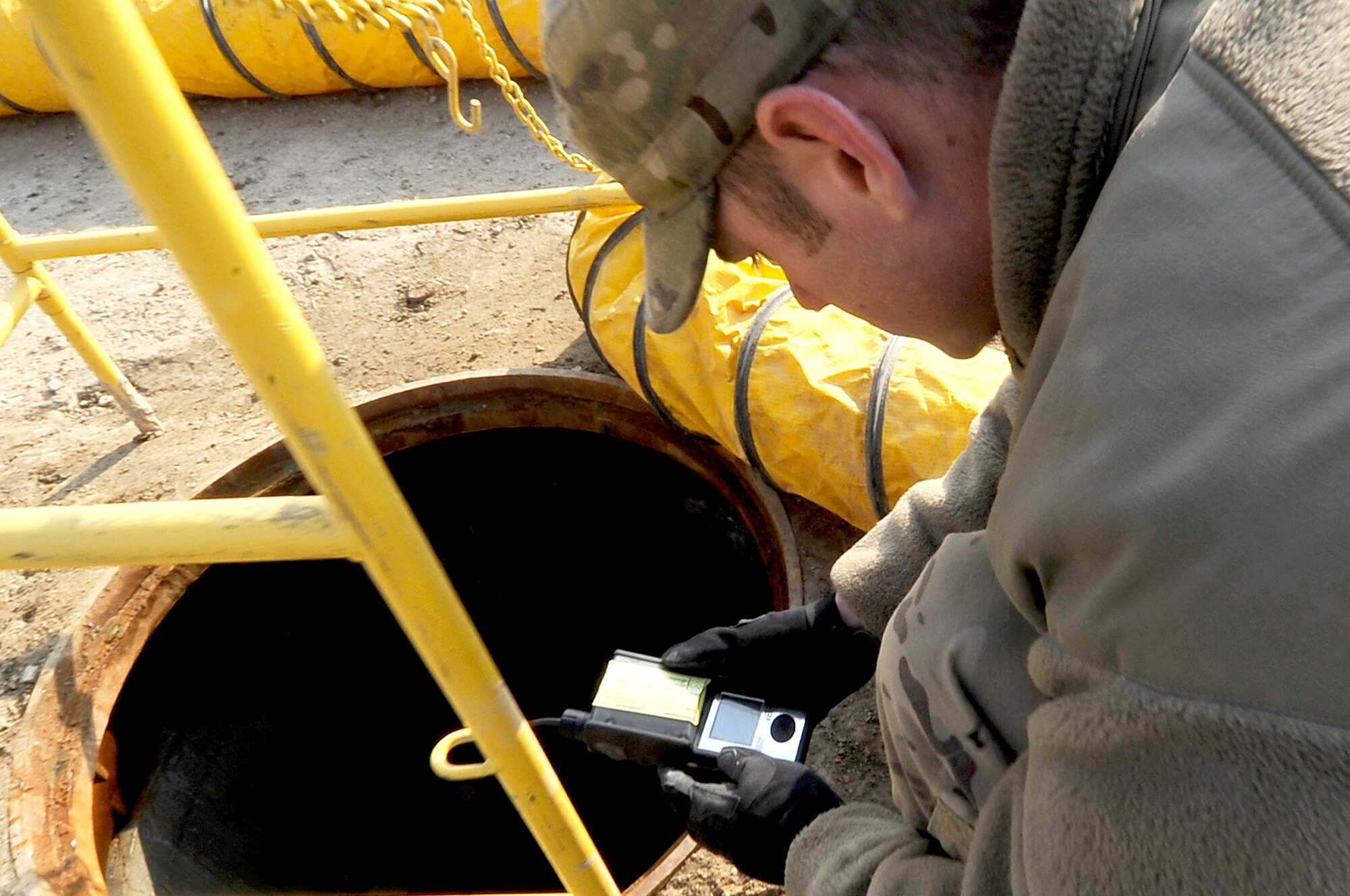 Staff Sgt. Brian Olsen, 455th Expeditionary Communications Squadron, cable and antenna systems technician, uses a multi-gas monitor to check for toxic gasses before going underground on Bagram Airfield, Jan. 9, 2013. Olsen is doing a final inspection of communication cables recently installed for future base development. (U.S. Air Force Photo/Master Sgt. Jun Kim)