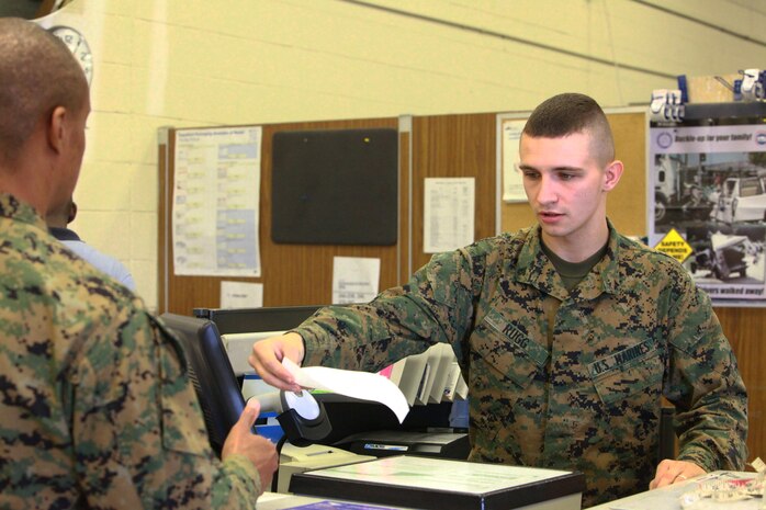 Lance Cpl. Aaron W. Rugg, a Connellsville, Pa., native, and postal clerk with Combat Logistics Regiment 27, 2nd Marine Logistics Group, currently working at the main post office aboard Camp Lejeune, N.C., gives a customer a receipt during checkout Jan. 10, 2013. Point of sale terminals automatically print receipts after all shipping information is entered for a customer’s package.