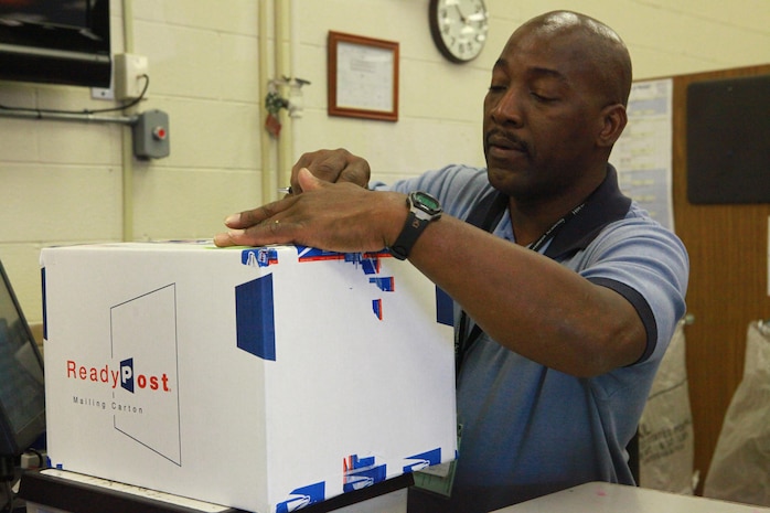 Lawrence Petteway, a postal clerk at the main post office aboard Camp Lejeune, N.C., places a shipping label on a package Jan. 10, 2013. Petteway used a point of sale terminal to input shipping information before he readied the package for mailing. 