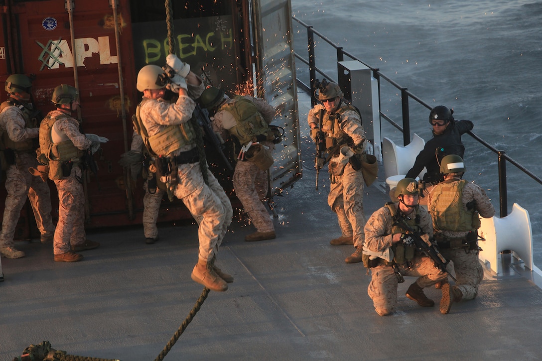 Marines with the 1st Marine Special Operations Battalion, U.S. Marine Corps Forces, Special Operations Command breach a cargo container as others rappel from a CH-47 helicopter onto the deck of a mock cargo ship during Visit, Board, Search and Seizure (VBSS) training with the 160th Special Operations Aviation Regiment near Camp Pendleton, Calif., Dec. 11. VBSS, which consists of maritime vessel boarding and searching, is used to combat smuggling, drug trafficking, terrorism and piracy. (U.S. Marine Corps photo by Cpl. Kyle McNally/Released)