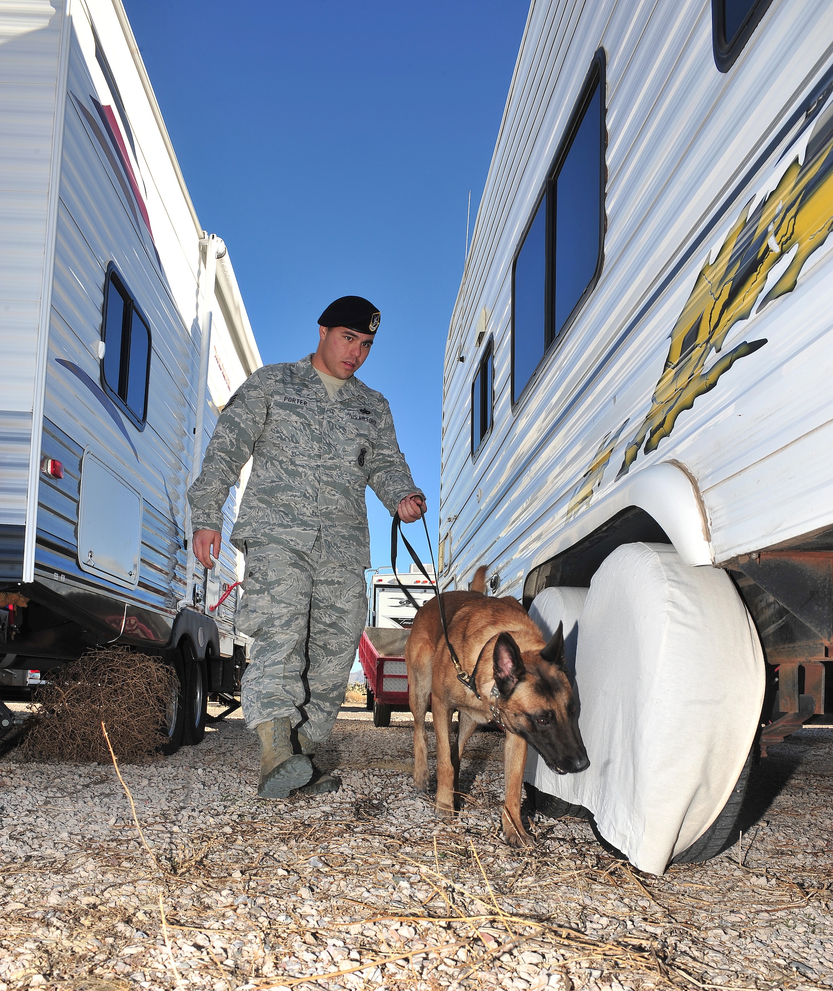 U.S. Air Force Staff Sgt. Ian Porter, 355th Security Forces Squadron military working dog handler, and Mushe, military working dog, search vehicles for explosives on Davis-Monthan Air Force Base, Ariz., Jan 9, 2012. Explosives had been hidden in a trailer park and Mushe had to find them as part of his training. (U.S. Air Force photo by Airman 1st Class Josh Slavin/Released)