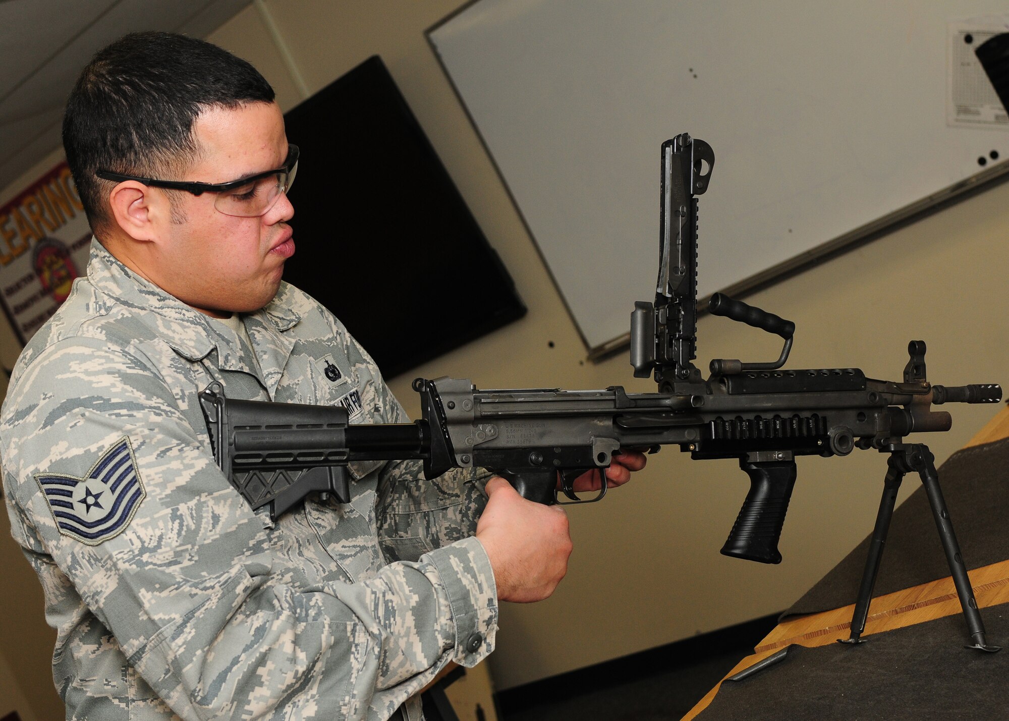 Tech. Sgt. Jesus Arias, 9th Security Forces Squadron NCO in charge of combat arms, breaks down and inspects a M-249 light machine gun at the combat arms facility on Beale Air Force Base, Calif., Jan. 10, 2013. Tech Sgt. Arias and his team train Team Beale on multiple weapons. (U.S. Air Force photo by Senior Airman Allen Pollard/Released)