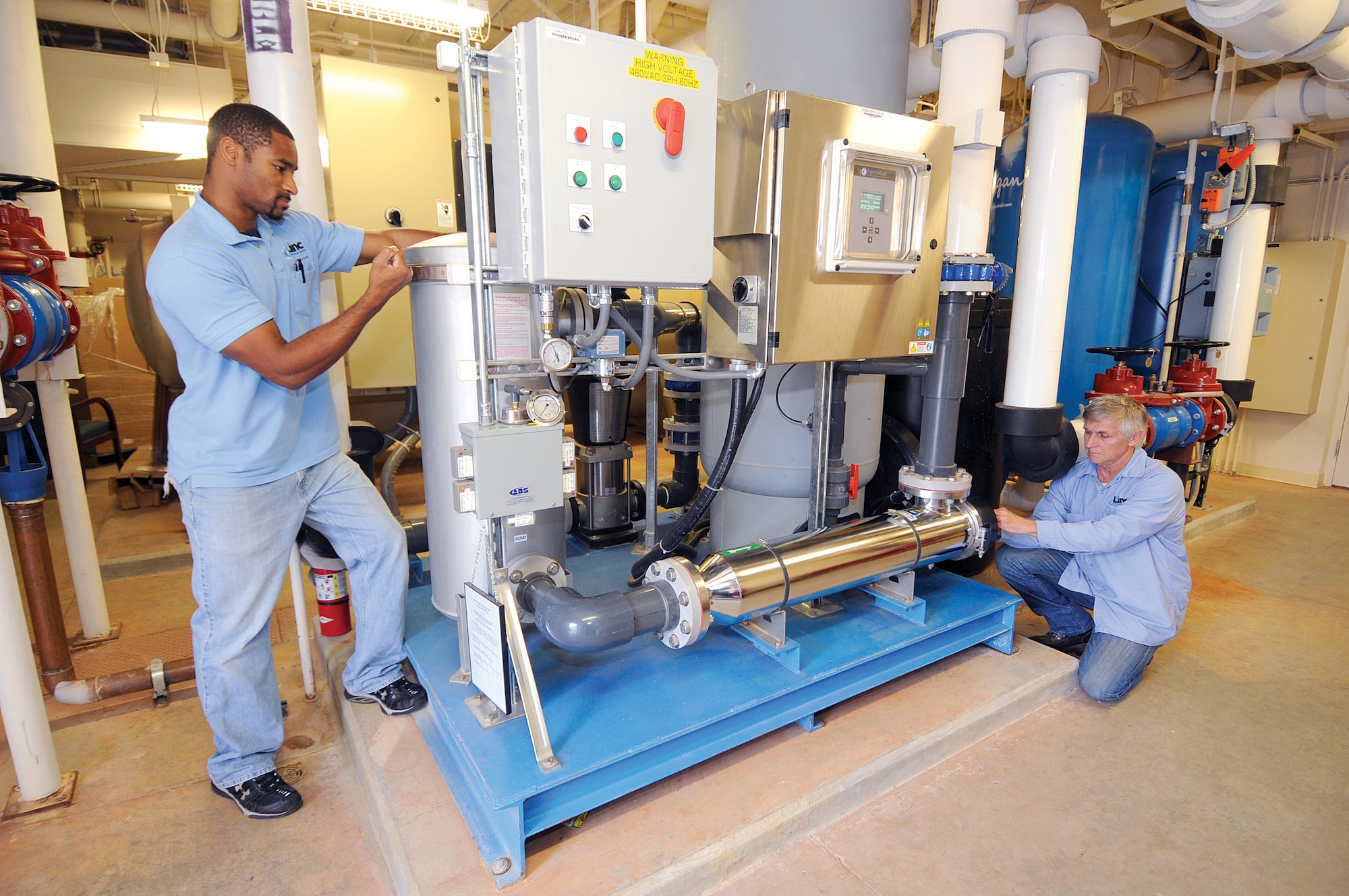 Air Force photo by Margo Wright
Phillip Starks, maintenance technician, left, and George Morgan, maintenance site manager of the new 72nd Medical Group facility, inspect a rain water collection system that filters and pumps the water to holding tanks where the water can be used through the facility for restrooms and in the cooling tower.  Unseen by most, this system saves money, energy and ensures a non-potable water system in case of a power outage.  This is one of many energy savers in systems and personnel actions that earned them a federal award for their reduced energy consumption accomplishments.
