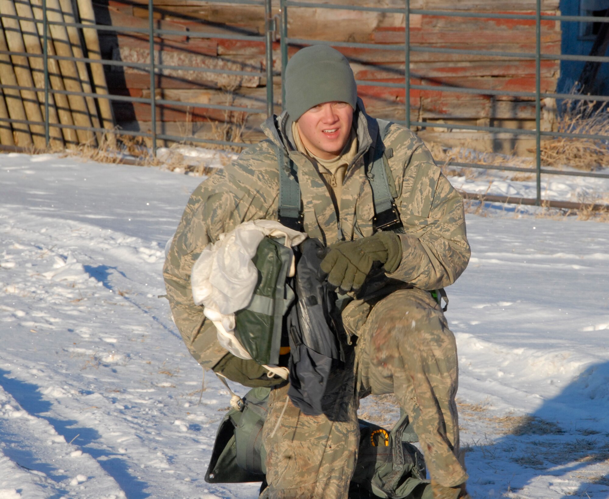 SIOUX FALLS, S.D.- Staff Sgt. Bo Martz, 175 Fighter Squadron Aircrew Flight Equipment technician, kneels in the snow with a paracute while instructing the Survival Evasion Resistance and Escape refresher training during combat survival training near Joe Foss Field, S.D. Jan. 6.  (National Guard photo by Senior Airman Amanda Bradshaw)(Released)