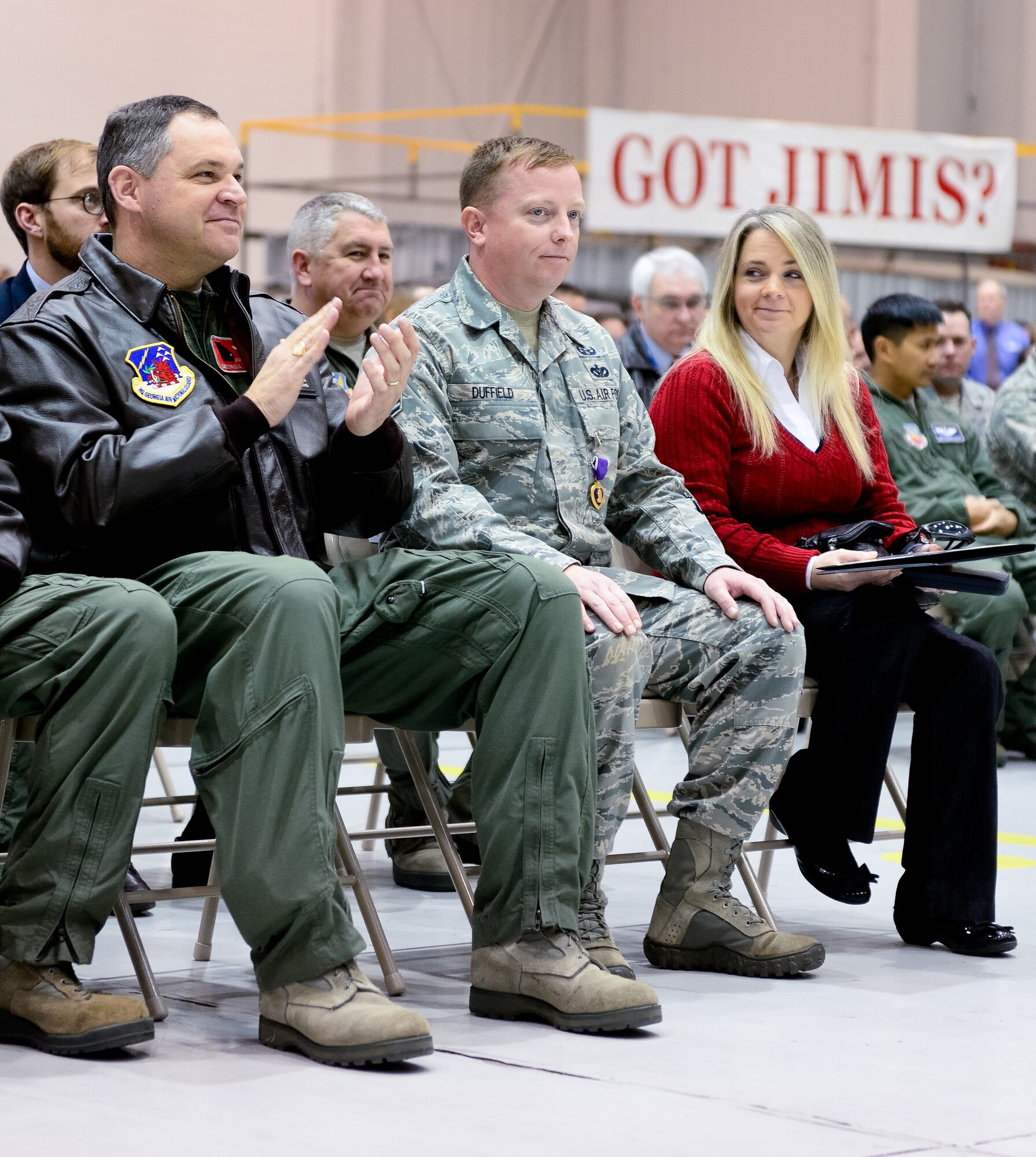 Donna Duffield glances at her husband, Air National Guard Tech. Sgt. Barry Duffield, 116th Civil Engineering Squadron, Explosive Ordnance Disposal Flight team leader, while he is applauded by Maj. Gen. Jim Butterworth, adjutant general, Georgia National Guard and other Georgia Guard leaders and members of Team Joint STARS, after Tech. Sgt. Duffield received the Purple Heart Medal from U.S Air Force Gen. Mike Hostage, commander, Air Combat Command during a ceremony at Robins Air Force Base, Ga., Jan. 7, 2013.  Duffield received the medal from Hostage for injuries sustained from an Improvised Explosive Device while deployed to Afghanistan in 2011.  During the same deployment, Duffield earned the Bronze Star and Air Force Combat Action Medal.  (National Guard photo by Master Sgt. Roger Parsons/Released)