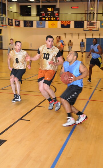 Tech. Sgt Ivan Vargas, right, Joint Special Operations Air Component joint operations specialist, evades Staff Sgt. Andrew Valence, 351st Air Refueling Squadron boom operator, and Staff Sgt. Everett Marshall, 351st ARS boom operator, during an intramural basketball game between the 100th Operations Group and the 352nd Special Operations Support Squadron Jan. 10, 2013, at the Hardstand Fitness Center on RAF Mildenhall, England. The 352nd SOSS were victorious over the 100th OG with a score of 55-41. (U.S. Air Force photo by Airman 1st Class Dillon Johnston/Released)