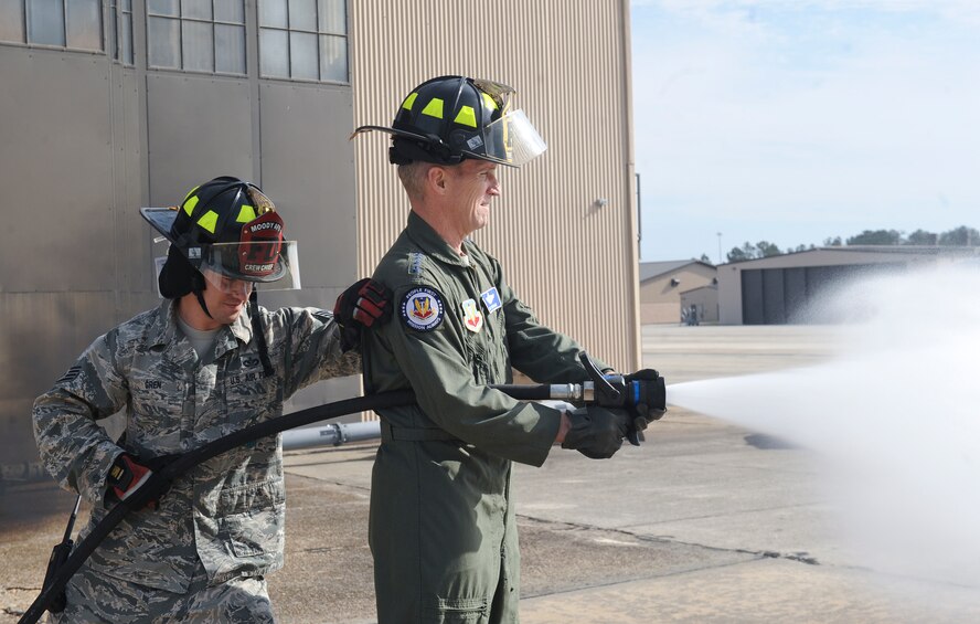 U.S. Air Force Staff Sgt. Jordan Gren, 23d Civil Engineer Squadron fire protection crew chief, supports Gen. Mike Hostage, commander of Air Combat Command, as he opens a valve to test water pump pressure at Moody Air Force Base, Ga., Jan. 9, 2012. Hostage visited Moody for the first time as ACC commander. (U.S. Air Force photo by Airman 1st Class Olivia Bumpers/Released)