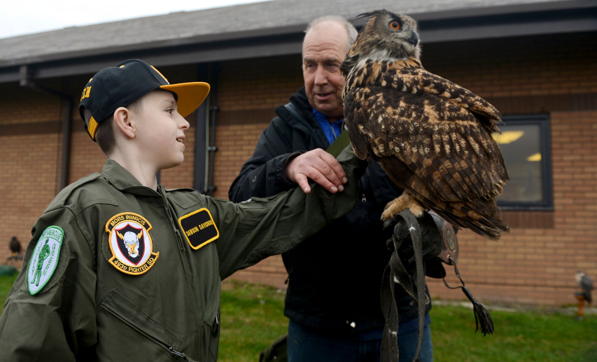 ROYAL AIR FORCE LAKENHEATH, England - Dawson Davidson, an 11-year-old Mildenhall resident, pets Twinkle, a 25-year-old eagle owl, with the help of Keith Mutton, Phoenix Bird Control falconer, during a "Pilot for a Day" event Jan. 8, 2013. During the event two local children received special-made flight suits, a flight in an F-15 simulator, an interactive squadron tour and an up-close viewing of an F-15C Eagle and HH-60G Pavehawk. (U.S. Air Force photo by Staff Sgt. Stephen Linch)