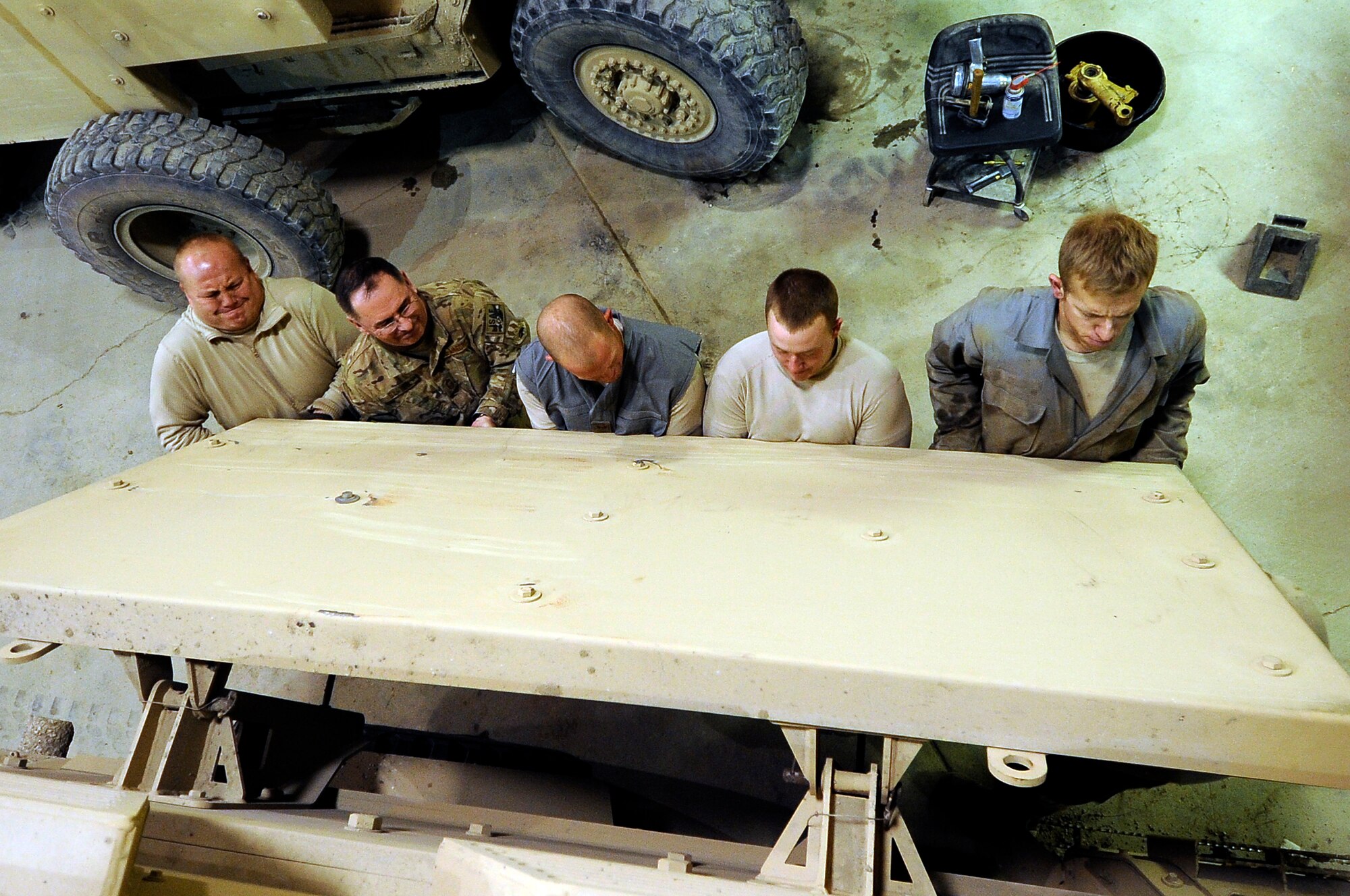 Members of 455th Logistical Readiness Squadron, tactical vehicle shop mechanics, work together to lower the Explosively Formed Penetrator on mine-resistant ambush protected (MRAP) vehicle after a tire replacement on Bagram Airfield, Jan. 9, 2013. The tactical vehicle shop is responsible for maintaining the Air Force’s MRAPs and other armored vehicles. (U.S. Air Force Photo/Master Sgt. Jun Kim)
