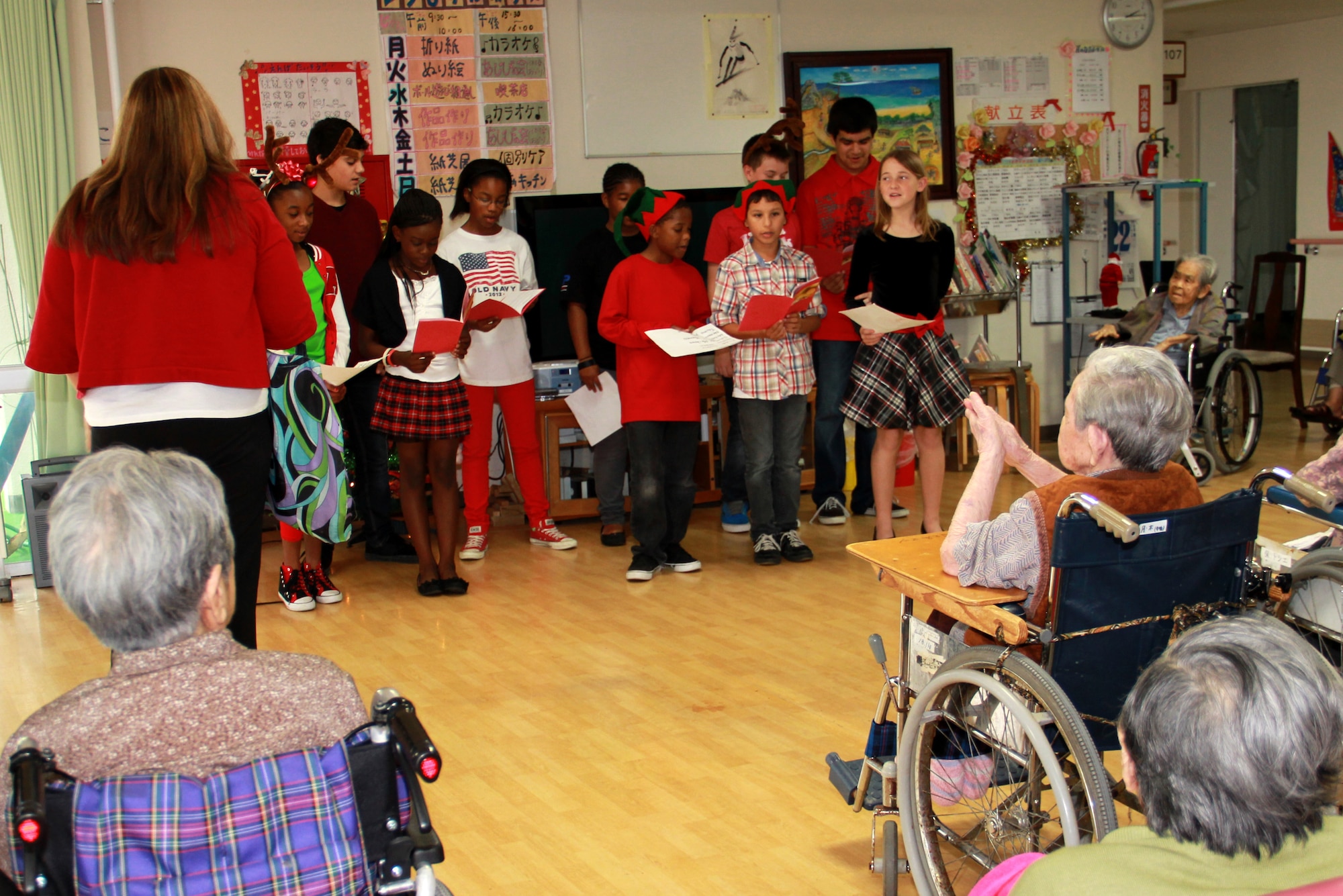 Kimberly Rogers leads Youth Center volunteers in performing Silent Night for the residents of Ichijoen, a local elder’s home on Okinawa, Japan, Dec. 22, 2012. Detachment 1, 554th RED HORSE Squadron has been partnering with Ichijoen from July to December after the Erwin Professional Military Education Center’s Class 12-5 hosted a volunteer project at Ichijoen. Two members from Det. 1 continued their relationship with the elder’s home. The squadron visits the home once a month to perform grounds work around the facility, interact with the residents, and provide donations when needed. Det. 1 recently partnered with the Youth Center and coordinated a holiday celebration with the residents, in which they performed Christmas songs for the residents. "The elders were happy to see the Youth Center children sing Christmas songs and dance,” said Yoko Sakiyama, the director of Ichijoen Elder’s Home. The squadron donated tissues, hand towels and lotion to the home. “I was impressed to hear about the volunteer spirit that Americans have. We thank the Youth Center and RED HORSE volunteers for visiting our elders during this busy holiday season." (U.S. Air Force photo/Tech. Sgt. Brian Dieckmann)