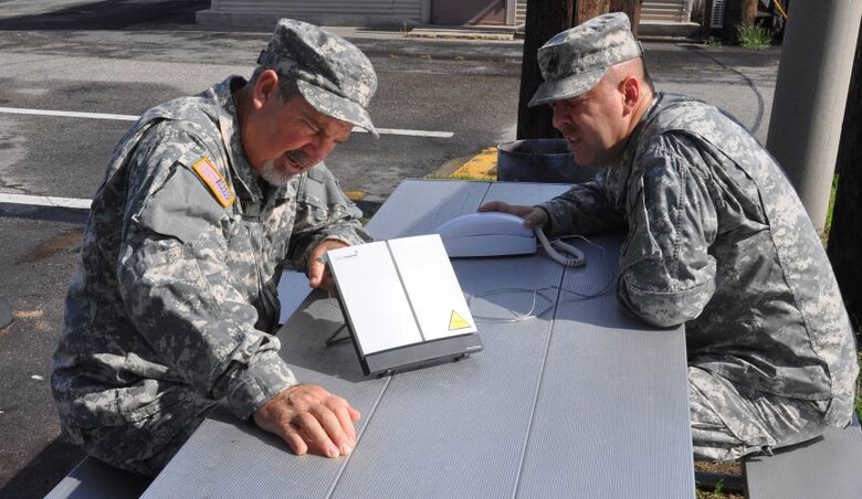 Jim Hynum (left) and Sgt. 1st Class Jeffrey Moran set up a broadband global area network at Far East District compound in Seoul, South Korea, in preparation for the annual combined force exercise, Ulchi Freedom Guardian. 