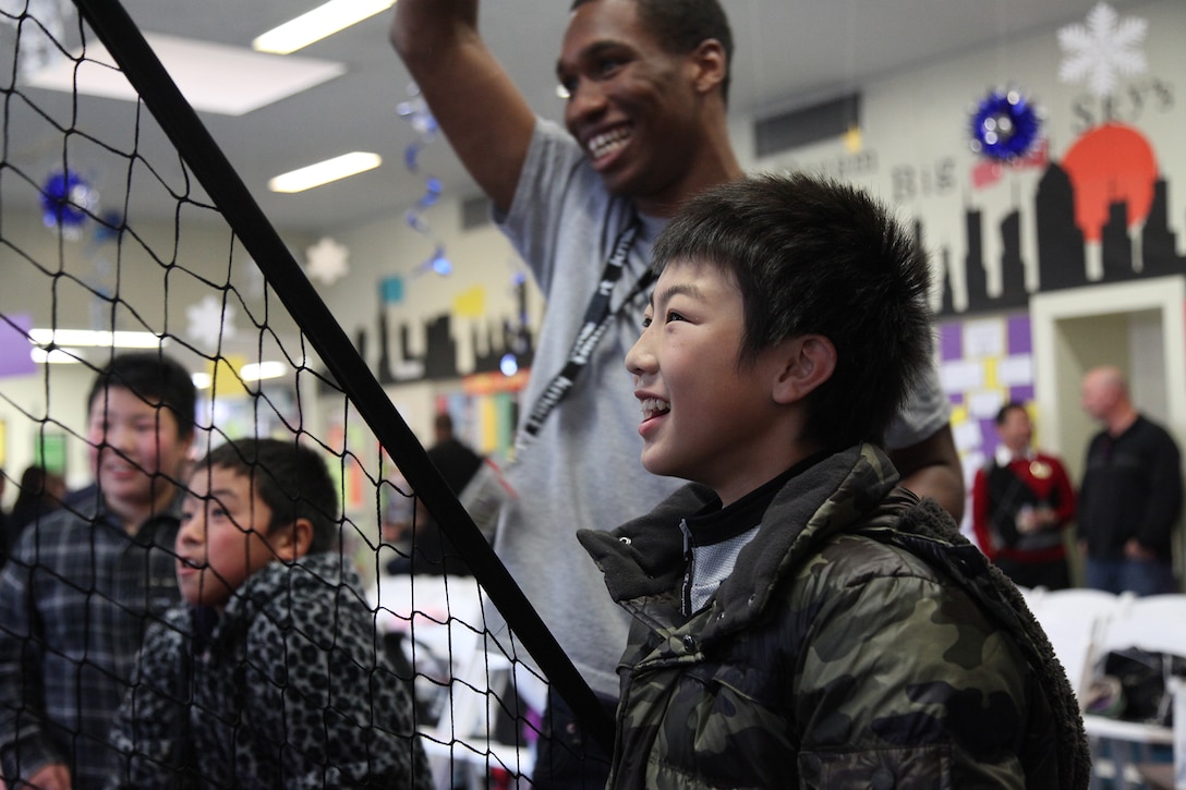 Yoshihito Sakurada watches and smiles while Columbus Wilson III scores a basket Jan. 11 at the Camp Foster Youth Center. Sakurada along with 23 other students from Oshima elementary and middle schools are visiting Okinawa as part of a four-day youth cultural exchange and homestay program. The fourth through eigth-grade children were invited to participate in the program. Sakurada is an 11-year-old fifth-grade student from Oshima, and Wilson is a program assistant at the Camp Foster Youth Center. (U.S. Marine Corps photo by /Released)

 
