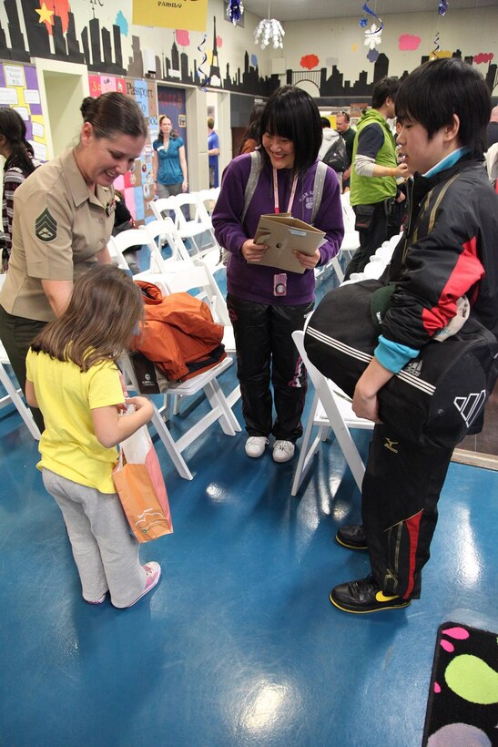 Staff Sgt. Cheryl L. King and her daughter, Ava, receive a gift from Naoya Murakami and Saya Onodera Jan. 11 at the Camp Foster Youth Center. Twenty-four children and six chaperones from Oshima Island are participating in the youth cultural exchange and homestay program. The students from Oshima prefecture are staying with military families that volunteered to host them during their visit on Okinawa. King is the training chief with S-3, training and operations, Marine Wing Headquarters Squadron 1, 1st Marine Aircraft Wing, III Marine Expeditionary Force. Murakami and Onadera are both students on Oshima Island, which was affected by the Great East Japan Earthquake and subsequent tsunami in March 2011. (U.S. Marine Corps photo by /Released)