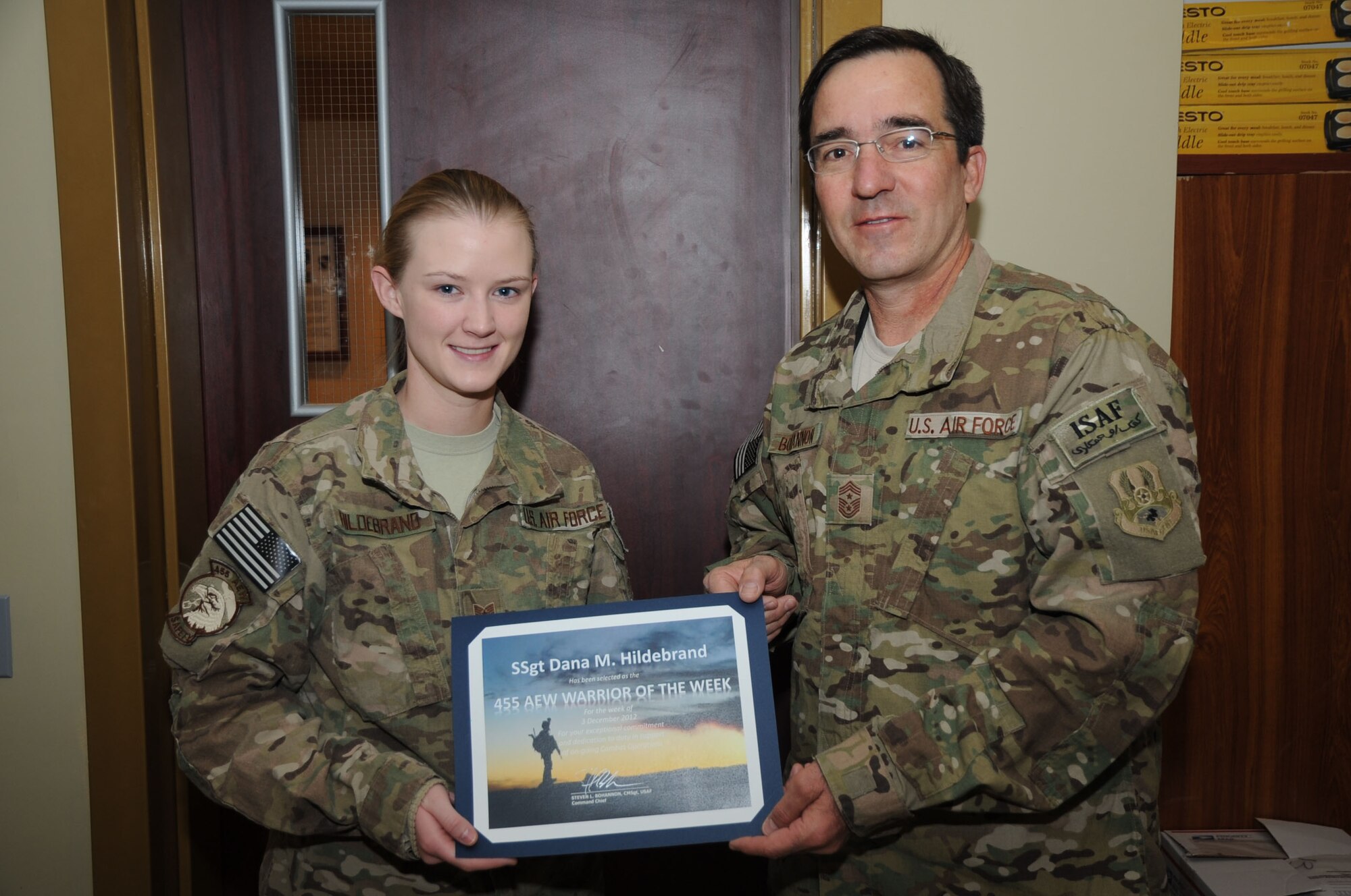 BAGRAM AIRFIELD, Afghanistan - Chief Master Sgt. Steve Bohannon, Command Chief Master Sergeant of the 455th Air Expeditionary Wing, presents the "Warrior of the Week" award to Staff Sgt. Dana Hildebrand, 455th Air Expeditionary Wing ground safety manager, Jan. 8, 2013. Hildebrand completed three annual unit safety inspections and conducted 15 no-notice inspections in addition to multiple additional duties and volunteer work. (U.S. Air Force photo/Staff Sgt. David Dobrydney)