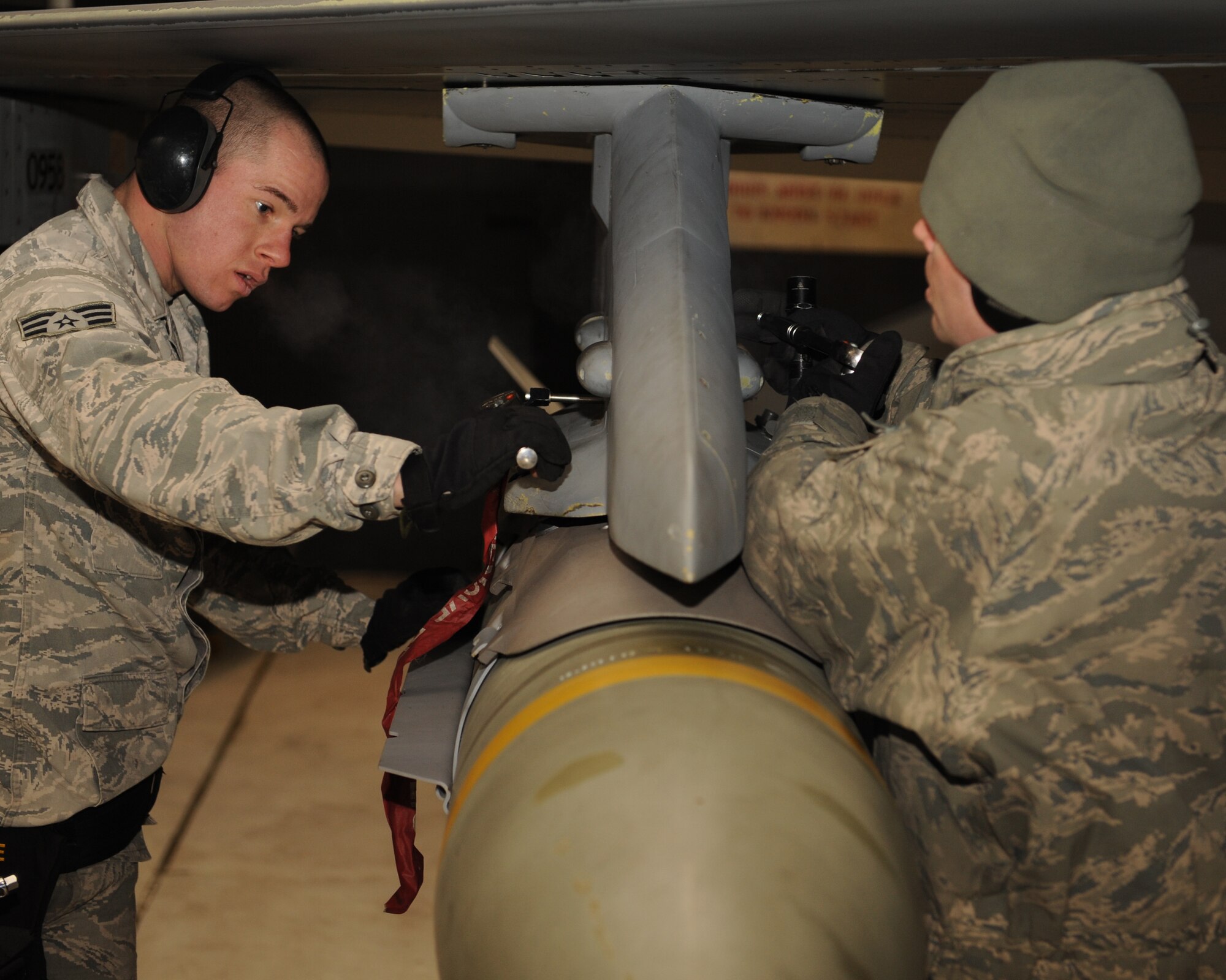 Senior Airman Kristopher Steele, left, and Staff Sgt. Chad Smith, 8th Aircraft Maintenance Squadron, secure a bomb to an F-16 Fighting Falcon at Kunsan Air Base, Republic of Korea, Jan. 14, 2013. Steele and Smith were preparing the aircraft for the first set of F-16 take-offs for the exercise, which assesses the readiness level of the base. (U.S. Air Force photo by Staff Sgt. Jonathan Fowler/Released)