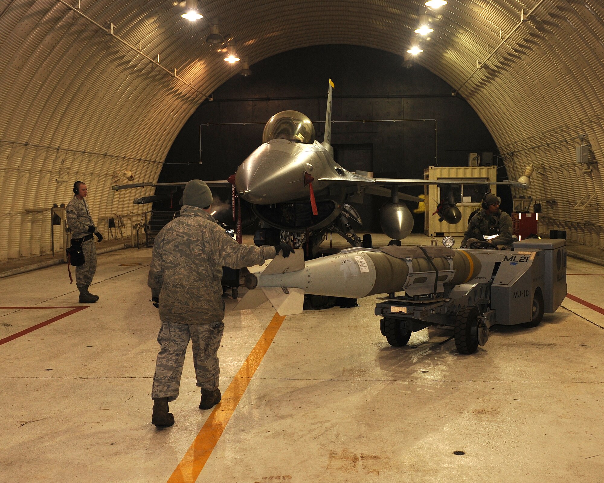 Senior Airman Kristopher Steele, Staff Sgt. Chad Smith and Airman 1st Class Kadeem Wright prepare to load a bomb onto an F-16 Fighting Falcon at Kunsan Air Base, Republic of Korea, Jan. 14, 2013. This was part of Beverly Midnight 13-1, an exercise which tests Airmen’s ability to respond to various scenarios such as mortar attacks and injured personnel. All three are members of the 8th Aircraft Maintenance Squadron. (U.S. Air Force photo by Staff Sgt. Jonathan Fowler/Released)
