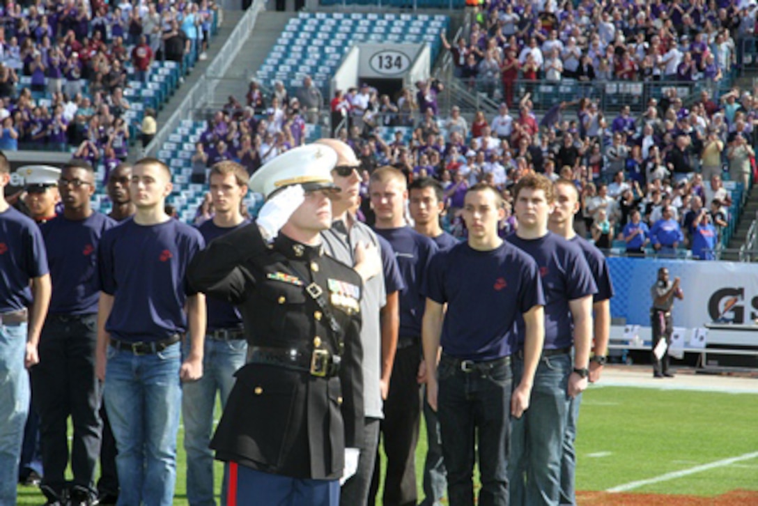 Captain Brandon Salter, the operations officer for Marine Corps Recruiting Station Jacksonville, salutes during the National Anthem after swearing in approximately 50 poolees to the Delayed Entry Program as a part of the pre-game show for the 2013 Taxslayer.com Gator Bowl in Jacksonville, Fla, Jan. 1.
