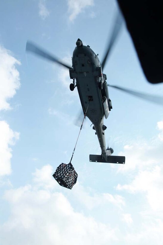 A MH-60S Knight Hawk with Combat Helicopter Squadron 23, USS Peleliu, brings supplies to the USS Peleliu during a replenishment-at-sea, Jan. 6. The 15th Marine Expeditionary Unit is deployed as part of the Peleliu Amphibious Ready Group as a U.S. Central Command theater reserve force, providing support for maritime security operations and theater security cooperation efforts in the U.S. 5th Fleet area of responsibility. (U.S. Marine Corps photo by Cpl. John Robbart III)