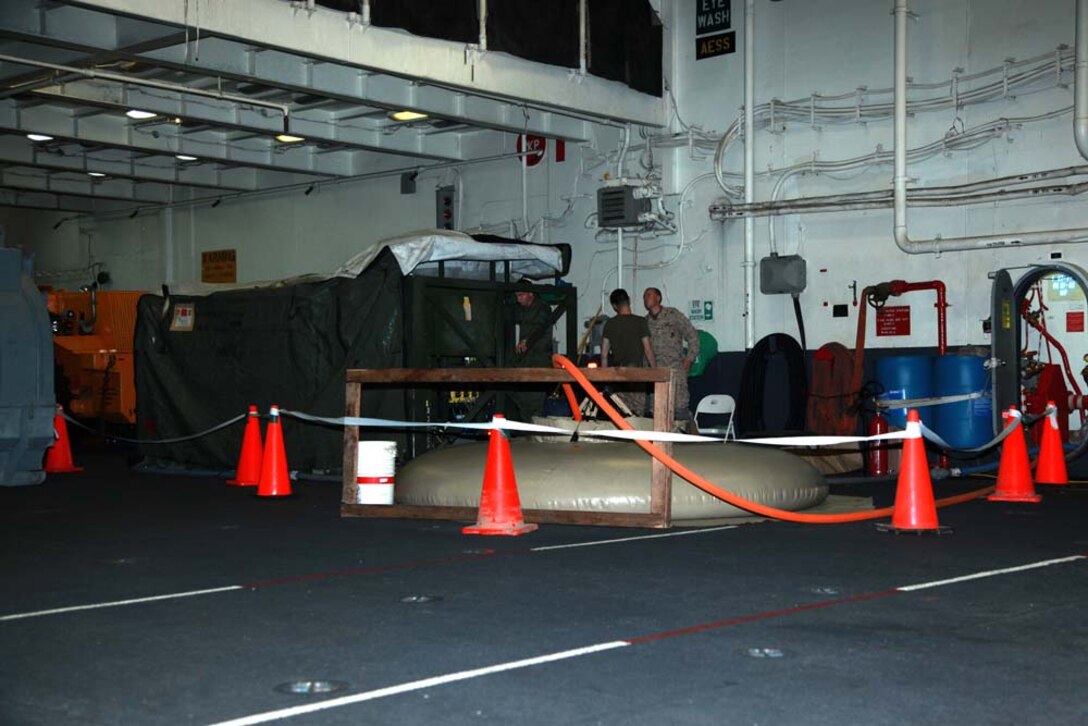 Marines with the Engineer Detachment, Combat Logistics Battalion 15, 15th Marine Expeditionary Unit, set up their Tactical Water Purification System in the hangar bay of the USS Peleliu, Jan. 3. The Marines are keeping their skills sharp and assisting the ship by providing 22,000 gallons per day. The 15th MEU is deployed as part of the Peleliu Amphibious Ready Group as a U.S. Central Command theater reserve force, providing support for maritime security operations and theater security cooperation efforts in the U.S. 5th Fleet area of responsibility. (U.S. Marine Corps photo by Cpl. John Robbart III)
