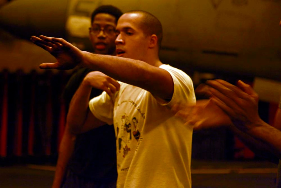 Aviation support equipment technician 2nd Class Juan A. Diaz, USS Peleliu, sings a song with members of his Capoeira class in the ship's hangar bay, Dec. 6. Capoeira is a form of dancing and martial arts, and the classes are taught to give Marines and sailors a way to decompress in their off-time. The 15th MEU is deployed as part of the Peleliu Amphibious Ready Group as a U.S. Central Command theater reserve force, providing support for maritime security operations and theater security cooperation efforts in the U.S. 5th Fleet area of responsibility. Diaz, 28, is from Bronx, N.Y. (U.S. Marine Corps photo by Cpl. John Robbart III)