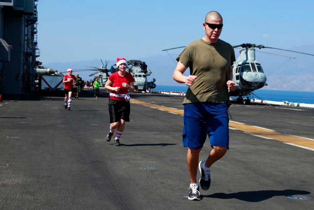 Marines and sailors with the 15th Marine Expeditionary Unit and Peleliu Amphibious Ready Group participate in a 5K fun run on the flight deck of the USS Peleliu, Dec. 15. The 15th MEU is deployed as part of the Peleliu ARG as a U.S. Central Command theater reserve force, providing support for maritime security operations and theater security cooperation efforts in the U.S. 5th Fleet area of responsibility. (U.S. Marine Corps photo by Cpl. John Robbart III)