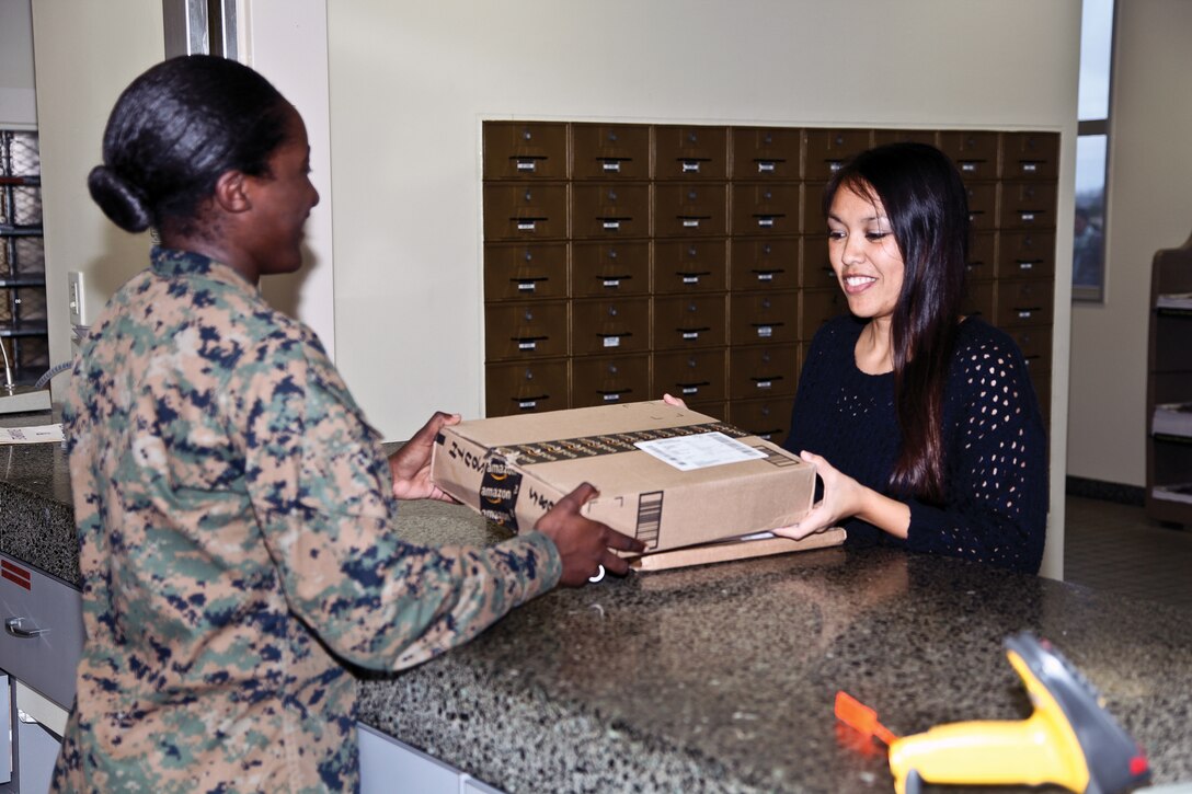 Lance Cpl. Shada F. Middleton, left, delivers a package to Jocelyn B. South at the post office on Camp Foster Jan. 8. Middleton is a postal clerk with Company A, Headquarters and Service Battalion, Marine Corps Base Camp Butler, Marine Corps Installations Pacific. South is a military family member.