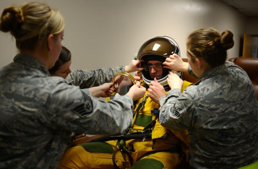 U.S. Air Force Staff Sgt. Vanessa Jordan, left, 9th Physiological Support Squadron launch and recovery technician, uses a mirror to confirm placement of U-2 pilot Capt. Travis’ specialized glasses within his helmet as Staff Sgt. Heather Doyle and Senior Airman Meghan Mattingly assist Jan. 8, 2013, at Beale Air Force Base, Calif. Dawning of the highly specialized full pressure suit requires a team of physiological support personnel. The squadron is the only one of its kind in the Department of Defense, with the responsibility of ensuring survivability of the nation's team of U-2 pilots. (U.S. Air Force photo by Airman 1st Class Drew Buchanan/Released)
