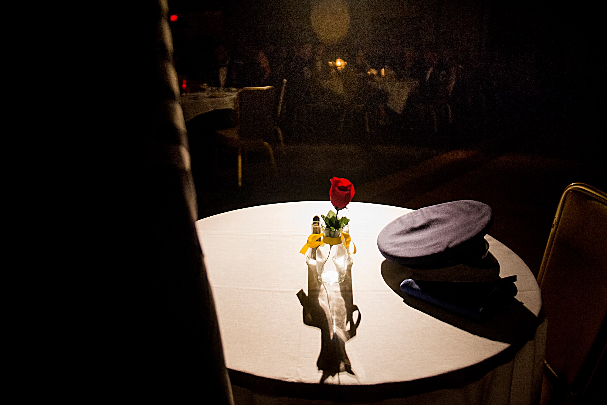 A prisoner of war/missing in action table is displayed in a spotlight during a chief recognition ceremony Jan. 12, 2013, at Moody Air Force Base, Ga. The display was in honor of U.S. Air Force Chief Master Sgt. Melvin Rash, a 41st Tactical Airlift Squadron C-130 Hercules loadmaster, who has been listed as missing in action since May of 1968. (U.S. Air Force photo by Staff Sgt. Jamal D. Sutter/Released)
