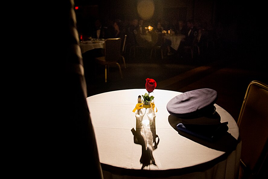A prisoner of war/missing in action table is displayed in a spotlight during a chief recognition ceremony Jan. 12, 2013, at Moody Air Force Base, Ga. The display was in honor of U.S. Air Force Chief Master Sgt. Melvin Rash, a 41st Tactical Airlift Squadron C-130 Hercules loadmaster, who has been listed as missing in action since May of 1968. (U.S. Air Force photo by Staff Sgt. Jamal D. Sutter/Released)
