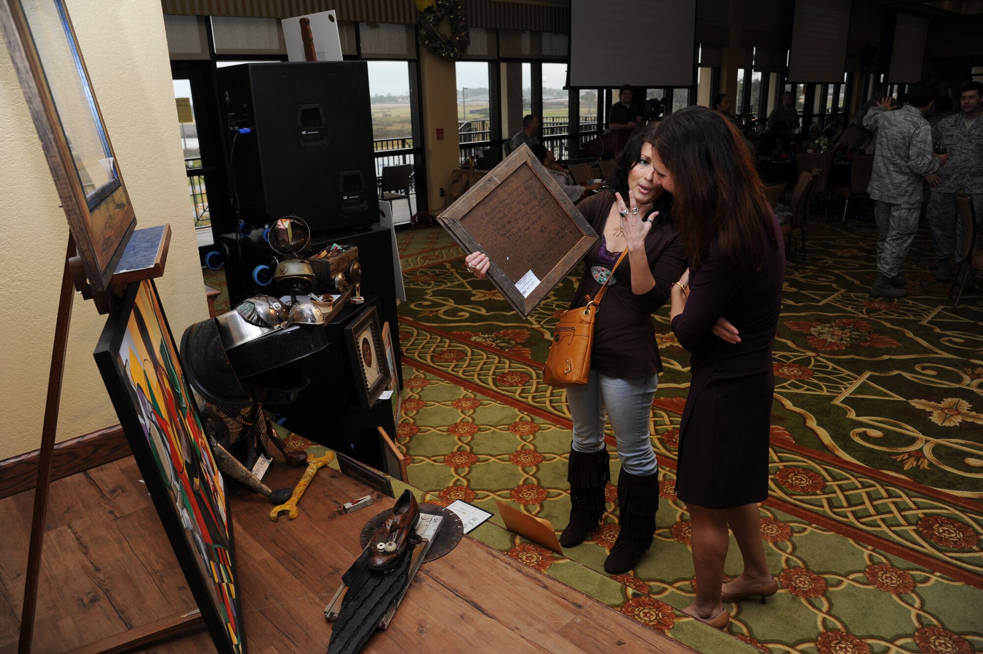 Romy Simpson, Negrotto’s Gallery, shows Lisa Spacy, spouse of Brig. Gen. Brad Spacy, 81st Training Wing commander, the display of art work at the annual Dr. Martin Luther King Jr. Memorial Luncheon Jan. 10, 2013, at the Bay Breeze Event Center, Keesler Air Force Base, Miss.  The guest speaker for the event was Lt. Gen. Darren McDew, 18th Air Force commander, Scott Air Force Base, Ill.  (U.S. Air Force photo by Kemberly Groue)