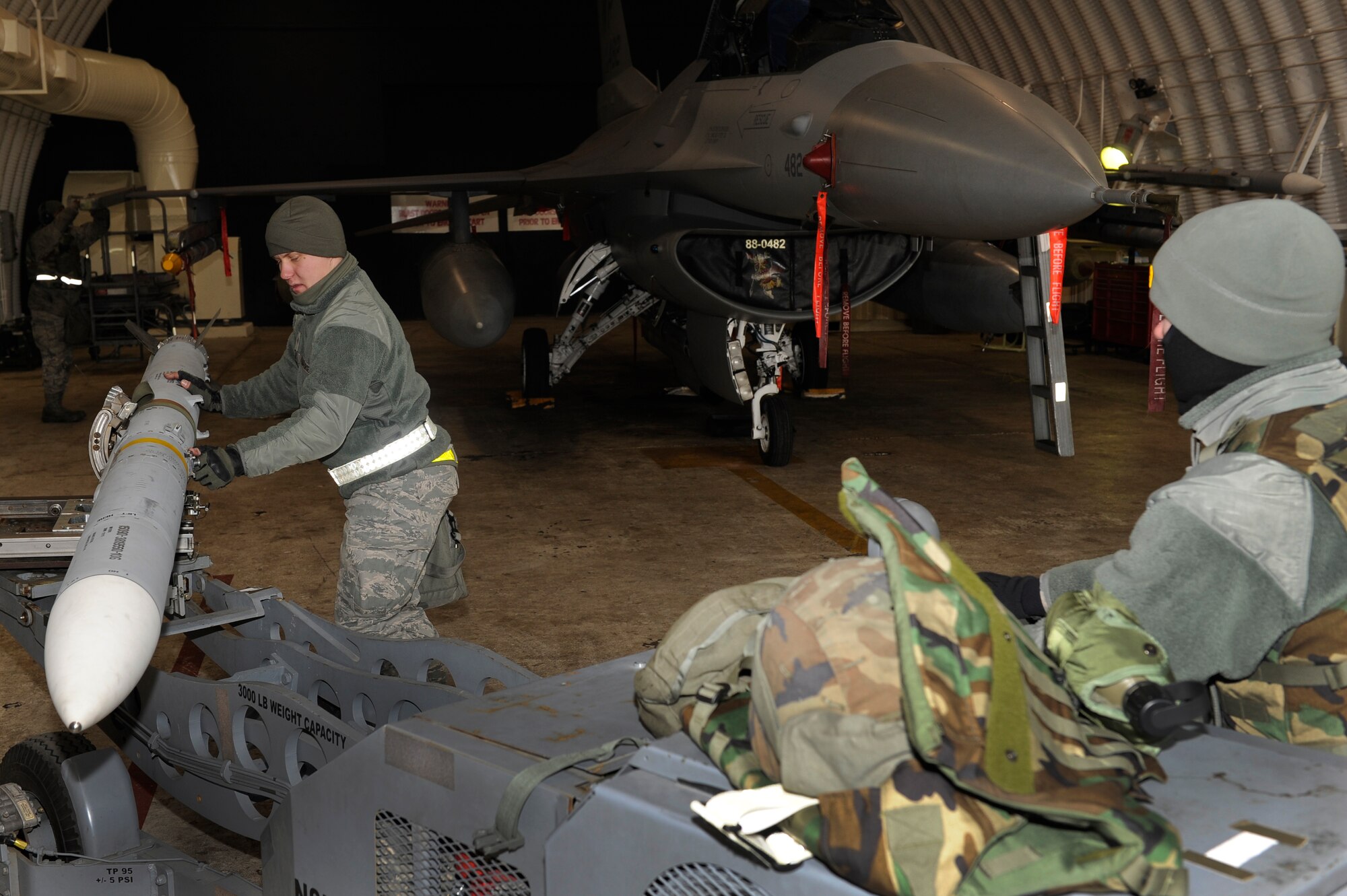 Senior Airman Vasiliy Zorin, 8th Aircraft Maintenance Squadron weapons load crew member, guides a missile toward an F-16 Fighting Falcon as Senior Airman Vincent Gleffe, 8th AMXS, drives a bomb lift truck during Beverly Midnight 13-1 at Kunsan Air Base, Republic of Korea, Jan. 14, 2013. The crew worked quickly to make the F-16 Fighting Falcon combat ready for the generation. (U.S. Air Force photo by Senior Airman Marcus Morris/Released)