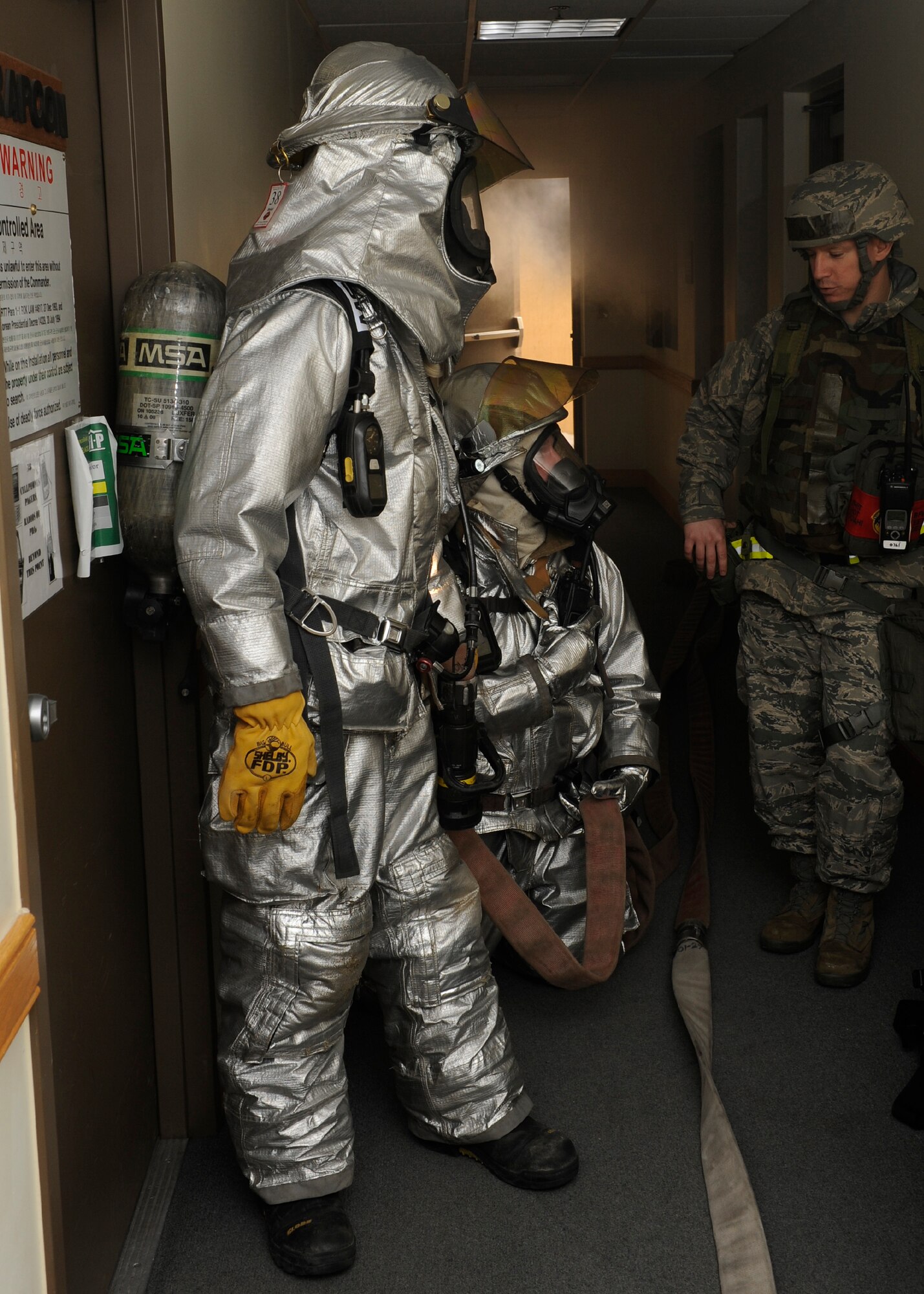 Staff Sgt. Jarrod Berry, right, 8th Civil Engineer Squadron exercise evaluation team, asks Senior Airman Aaron Strayhorn, and Staff Sgt. Rodger Halle, 8th CES firefighters, how they would get into the cipher-locked room to check for people during Beverly Midnight 13-1 at Kunsan Air Base, Republic of Korea, Jan. 14, 2013. After talking with their headquarters the team continued through the rest of the building checking for anyone left inside. (U.S. Air Force photo by Senior Airman Marcus Morris/Released)
