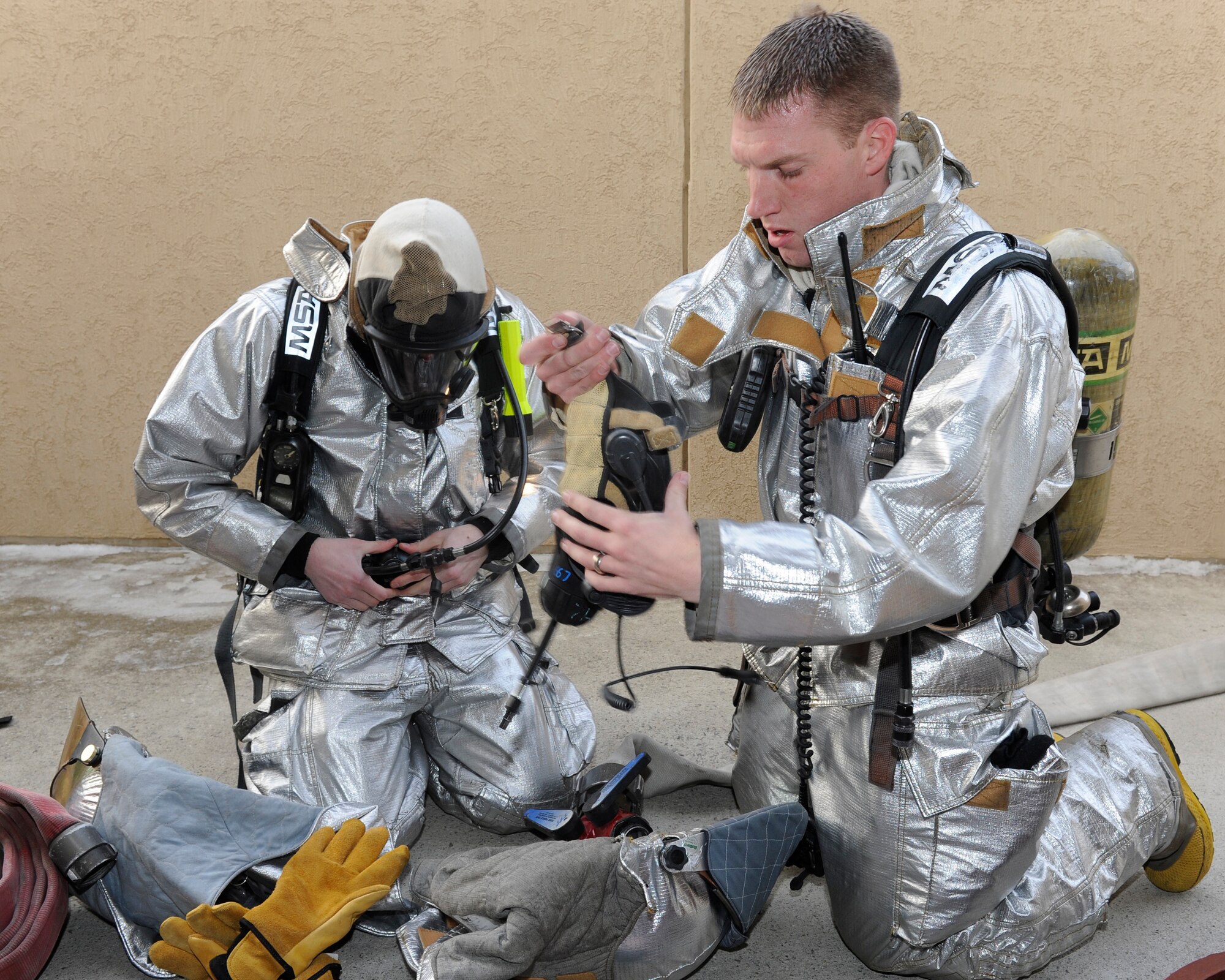 Senior Airman Aaron Strayhorn, left, and Staff Sgt. Rodger Halle, 8th Civil Engineer Squadron firefighters, don their masks after discovering a building fire during Beverly Midnight 13-1 at Kunsan Air Base, Republic of Korea, Jan. 14, 2013. Thescenario allowed the exercise evaluation team to observe the evacuees and firefighters response to the fire. (U.S. Air Force photo by Senior Airman Marcus Morris/Released)