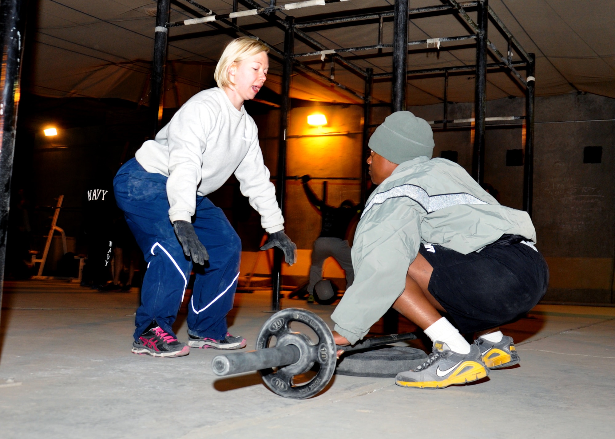 Capt. Lesley Lilly, 451st Expeditionary Force Support Flight commander and a volunteer CrossFit coach at Kandahar Airfield, shows an athlete proper form on overhead squats during the 5 a.m. CrossFit class on Jan. 14. Lilly, deployed here from Joint Base San Antonio-Lackland, coaches a 5 a.m. class six days a week. One of the most rewarding things about coaching is watching people develop and improve, she said. (U.S. Air Force photo/Master Sgt. Russell Martin)