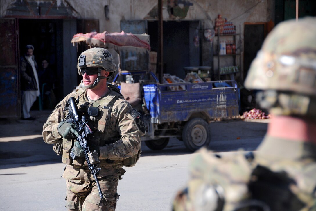 U.S. Army Spc. Joseph Henry, left, provides security on the street outside a meeting at a bank in Farah City, Afghanistan, Jan. 13, 2013. Henry is assigned to Provincial Reconstruction Team Farah.
