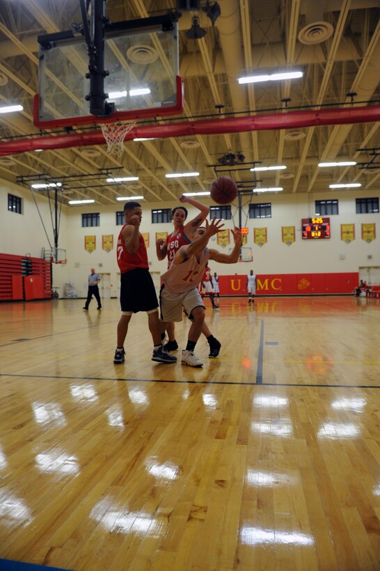 Marke Kowalik, player with Marine Corps Air Facility’s intramural basketball team, dives for the ball between two players from the Marine Corps Embassy Security Group team, Charles Jones and Madea Davis, at the Barber Physical Fitness Center on Jan. 14. MCESG wasn’t able to catch up in the second half and lost, 49-36. 