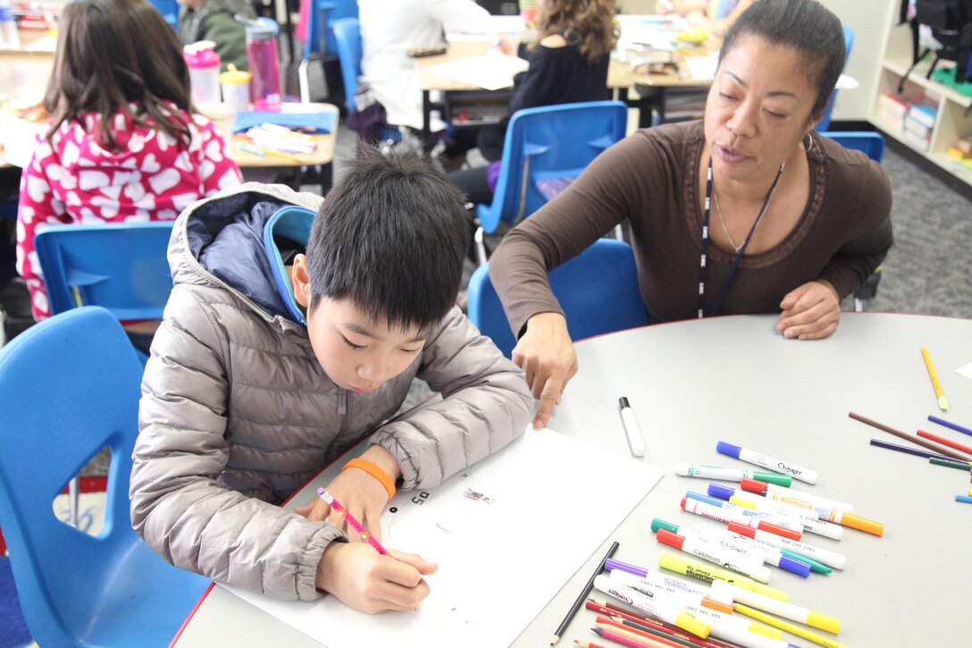 CAMP FOSTER, OKINAWA, Japan – Takumu Monma, left, colors a picture while Melanie Horton encourages him during art class Jan. 14 at E. C. Killin Elementary School on Camp Foster. Monma was a participant in the Marine Corps Community Services-sponsored, four-day youth cultural exchange program. During the program, 24 students from Oshima Island came to Okinawa to stay with volunteer Marine Corps families who showed them around Okinawa and introduced them to Marine Corps culture. Monma is a 12-year-old fifth-grader from Oshima. Horton is a fifth-grade teacher at E. C. Killin Elementary School. (U.S. Marine Corps photo by Lance Cpl. Daniel E. Valle/Released)