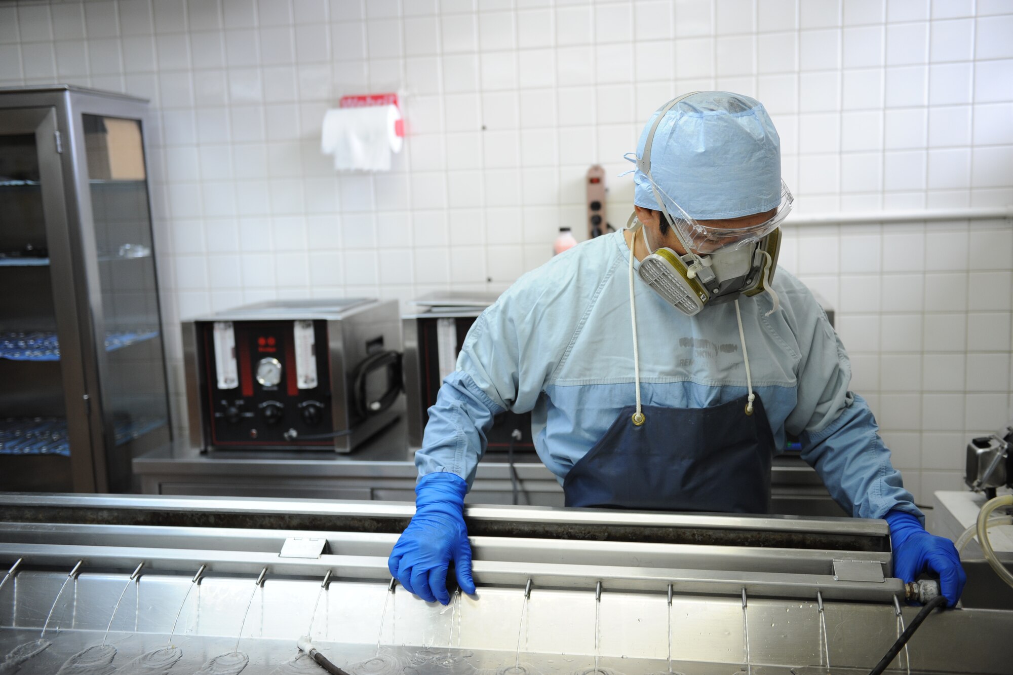 Kazu Ya Tamanaha, U.S. Air Force Mortuary funeral specialist, demonstrates the proper wear of the protective gear needed during the embalming processes at the USAF Mortuary on Camp Kinser, Japan, Jan. 9, 2013. The USAF Mortuary provides support to all military members, Department of Defense civilians and loved ones within the Western Pacific. (U.S. Air Force photo/ Airman 1st Class Brooke P. Doyle)