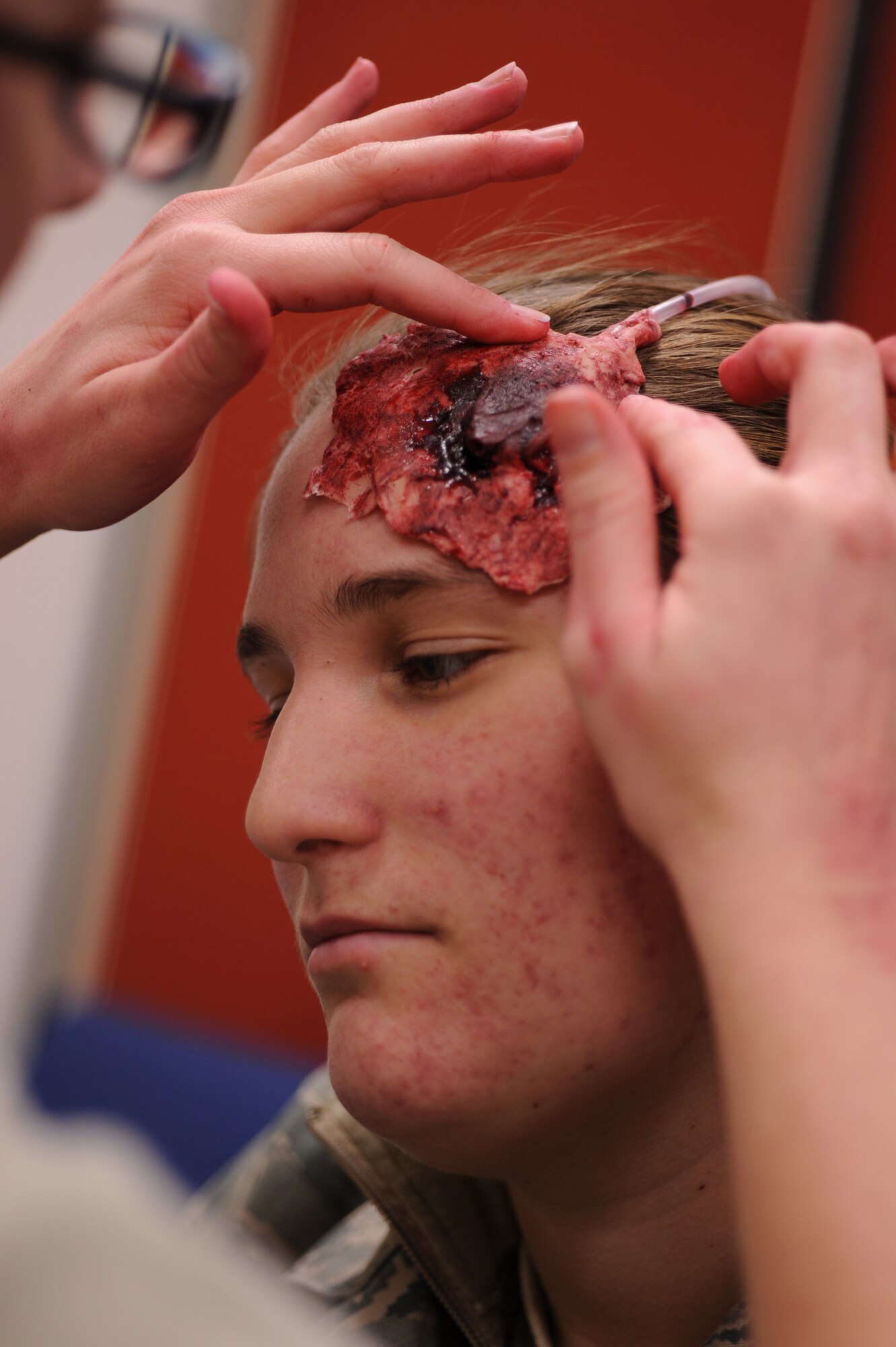 Staff Sgt. Jennifer Lively, 8th Fighter Wing moulage artist, applies a fake bullet wound to the head of Airman 1st Class Crystal MacGirvin, 8th FW role player, during Exercise Beverly Midnight 13-1 at Kunsan Air Base, Republic of Korea, Jan. 16, 2013. Lively makes the simulated wounds as realistic as possible to ensure personnel will respond more accurately while treating them. (U.S. Air Force photo by Staff Sgt. Jonathan Fowler/Released)
