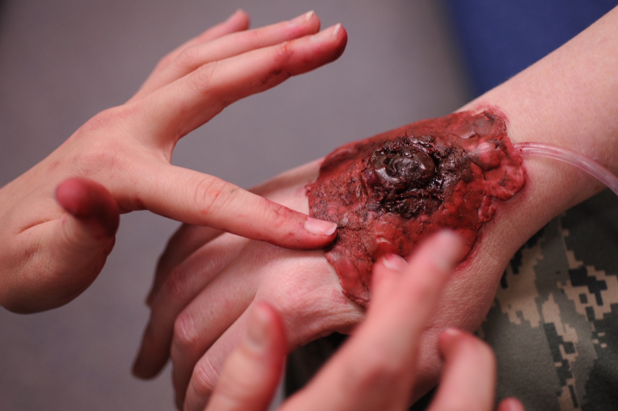 Staff Sgt. Jennifer Lively, 8th Fighter Wing moulage  artist, applies a fake bullet wound to the hand of Tech. Sgt. Frances Bland, 8th FW role player, during Exercise Beverly Midnight 13-1 at Kunsan Air Base, Republic of Korea, Jan. 16, 2013. Lively makes the simulated wounds as realistic as possible to ensure personnel will respond more accurately while treating them. (U.S. Air Force photo by Staff Sgt. Jonathan Fowler/Released)