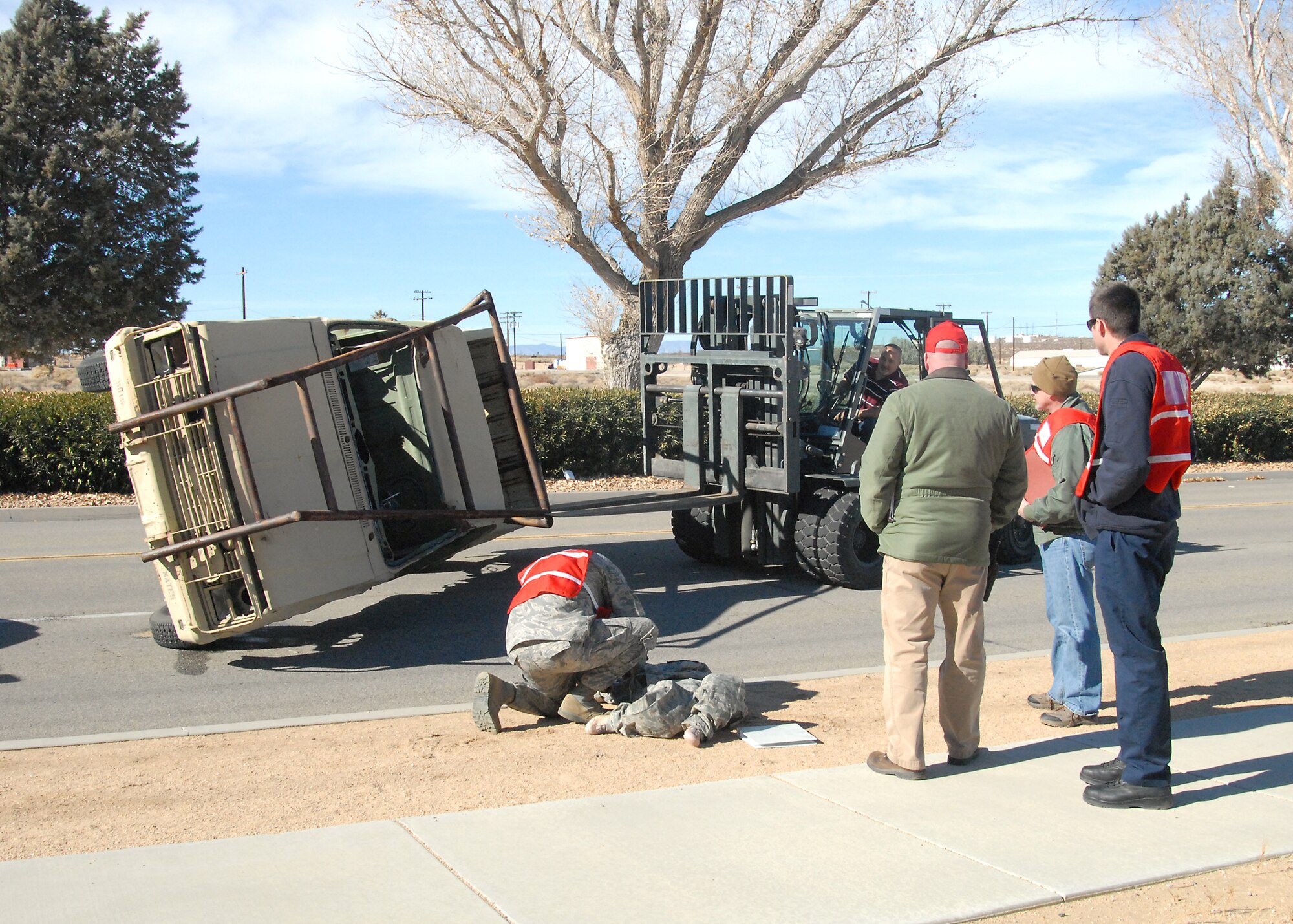 A forklift moves a training vehicle into place as part of a traffic accident scene before a 911 call was sent out to begin the HAZMAT exercise. (U.S. Air Force photo by Kenji Thuloweit)