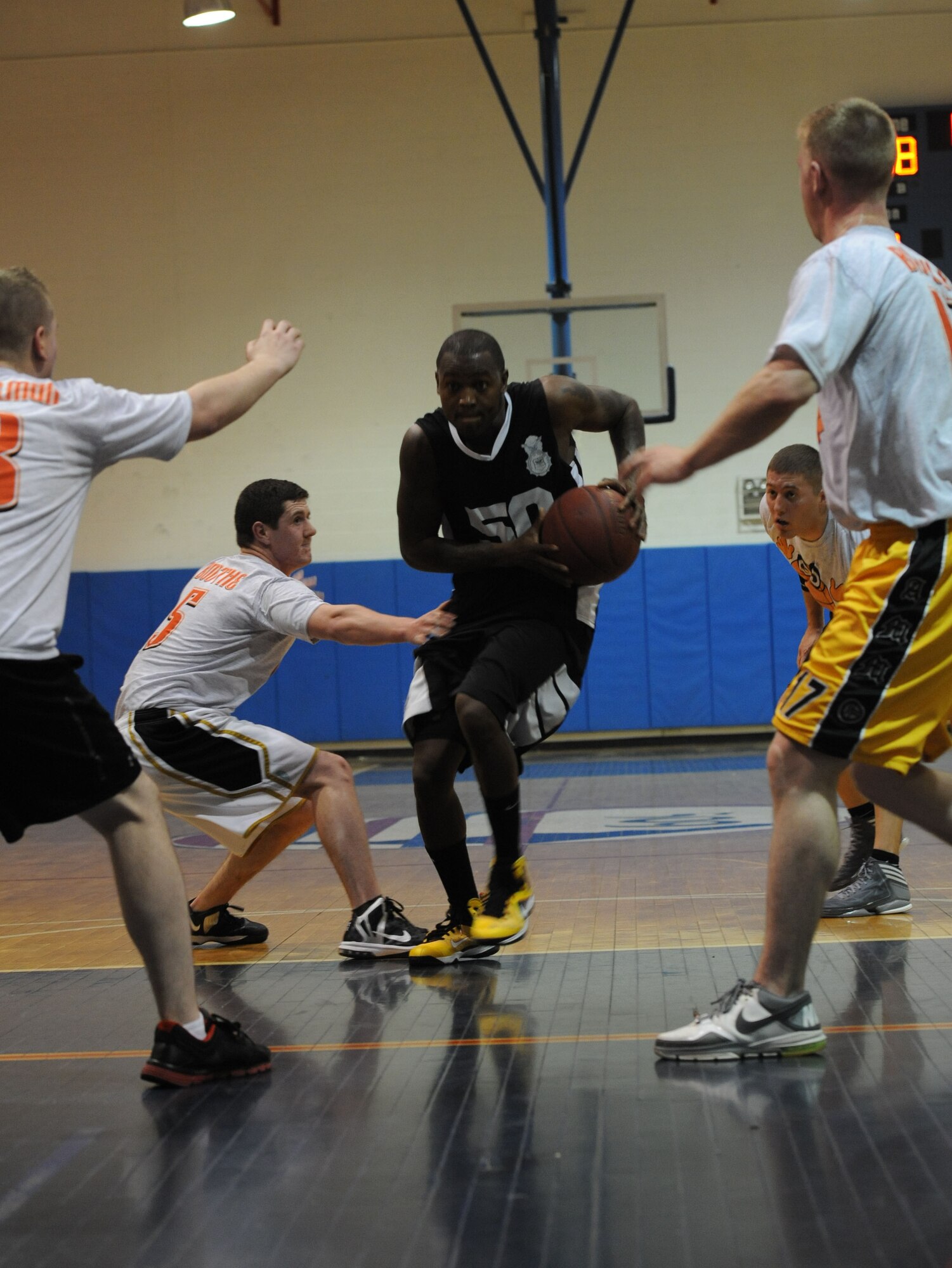 WHITEMAN AIR FORCE BASE, Mo. -- Antonio Chatman, 509th Security Forces-B intramural basketball team member, drives the lane as members of the 509th Aircraft Maintenance Squadron basketball team defend during their game Jan. 8. The 509th SFS-B earned a  52-42 victory. (U.S. Air Force photo/Staff Sgt. Nick Wilson) (Released)