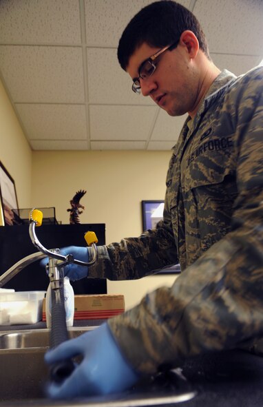 Airman 1st Class Bryan Pyszk, 2nd Operations Support Squadron aircrew flight equipment, cleans an oxygen hose from an aircrew helmet on Barksdale Air Force Base, La., Jan. 15. Airmen use a mild detergent, gauze pads and hot water when cleaning equipment. (U.S. Air Force photo/Airman 1st Class Benjamin Gonsier)